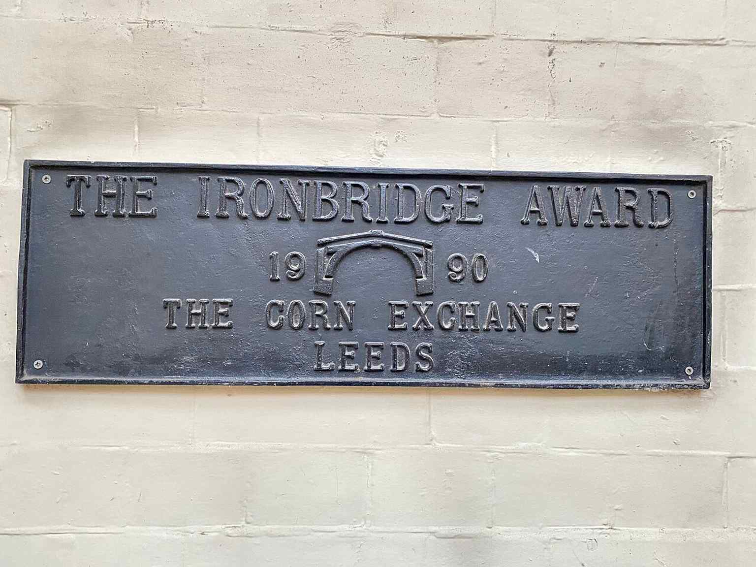 A plaque marking the building’s post-restoration recognition, recalling the Corn Exchange’s long life after its 1980s conversion to retail.