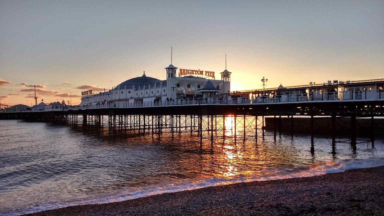 Sunset over the pier captures its famous illuminated promenade, part of the nightly glow from tens of thousands of bulbs.
