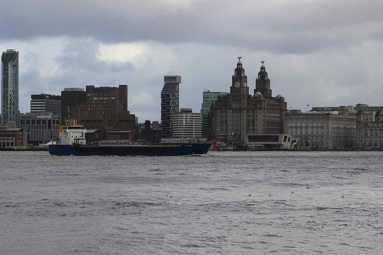 A riverside view with a ship in the foreground, linking the building to Liverpool’s maritime heritage and dockside skyline.