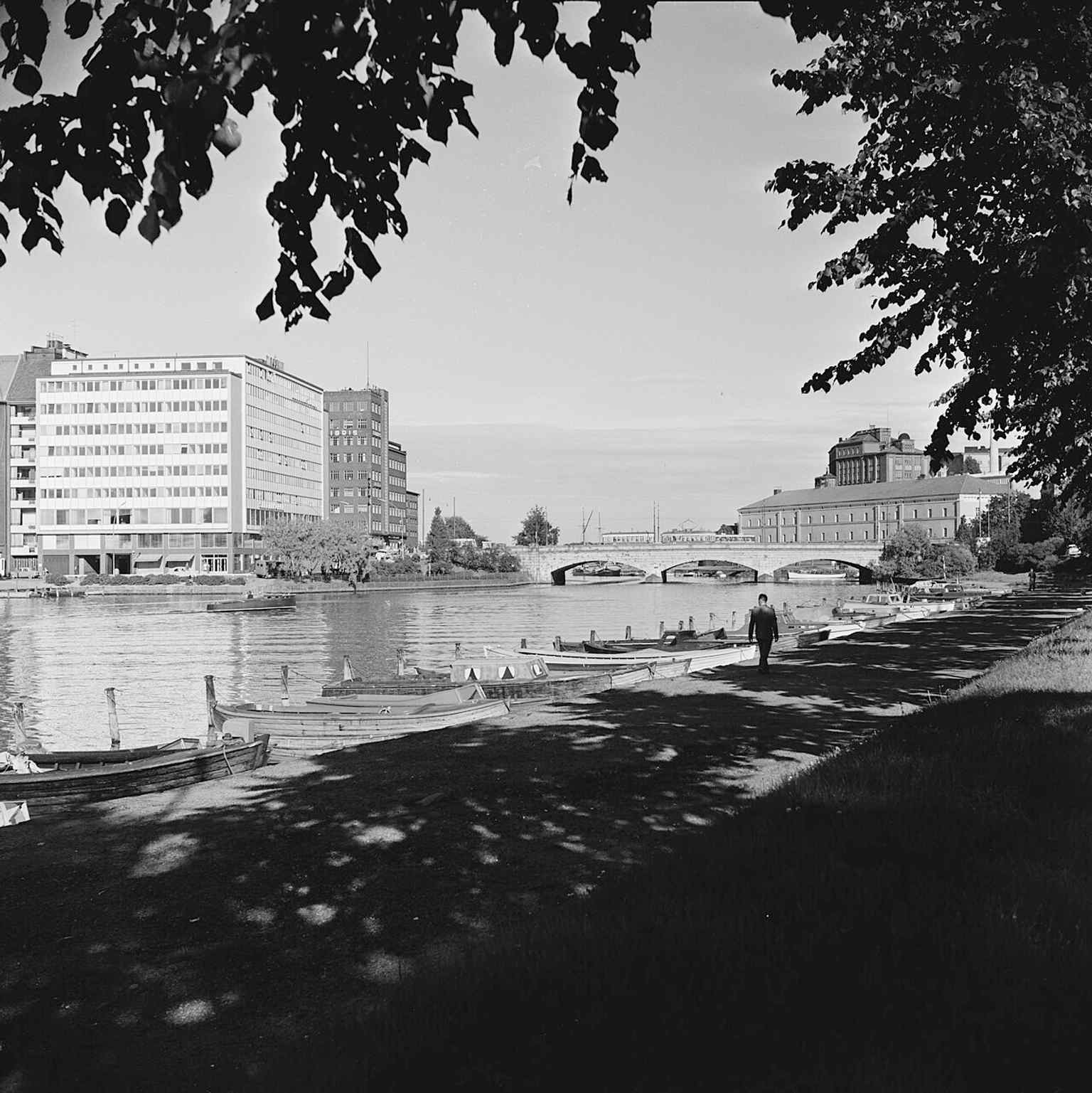 A wide 1958 view across Kaisaniemenlahti toward Siltasaari and Pitkäsilta, showing the bridge as an everyday crossing in central Helsinki.