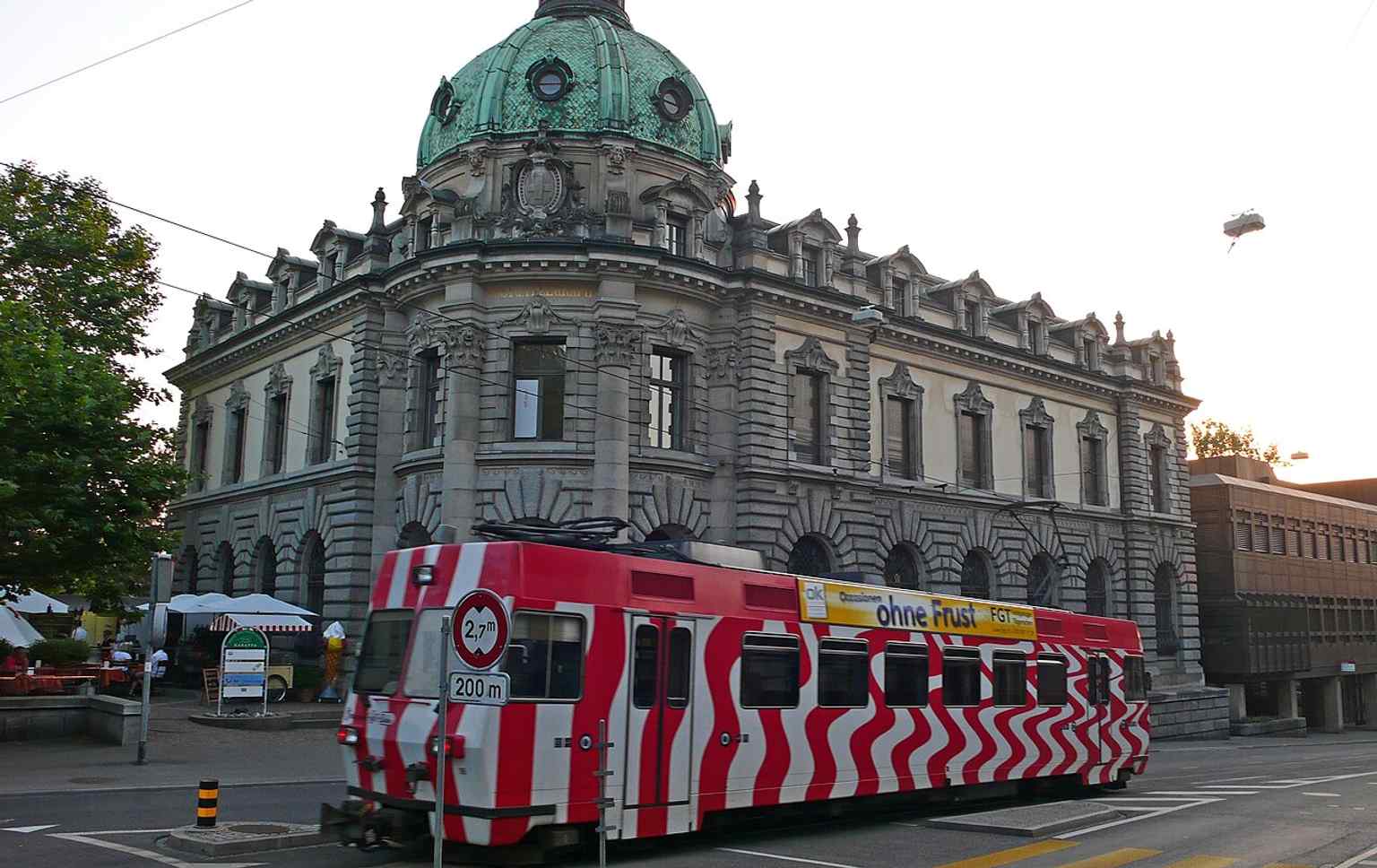 A Frauenfeld-Wil-Bahn train passes the post office, echoing a 1905 scene of the building woven into everyday street life and local transport.