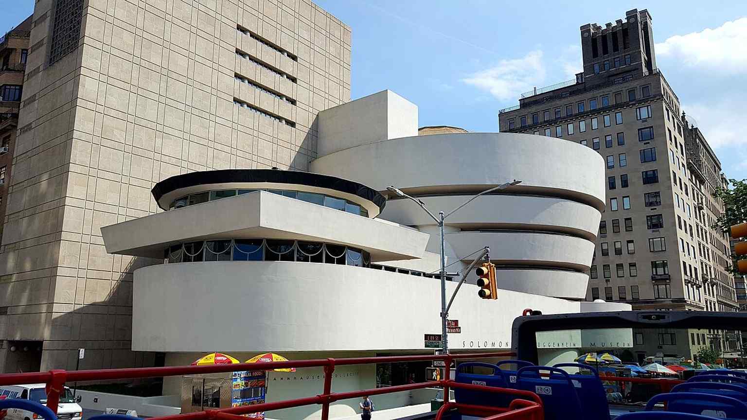 A wider street view of the Guggenheim on the Upper East Side, showing how its curved form contrasts with the straight grid of Manhattan.