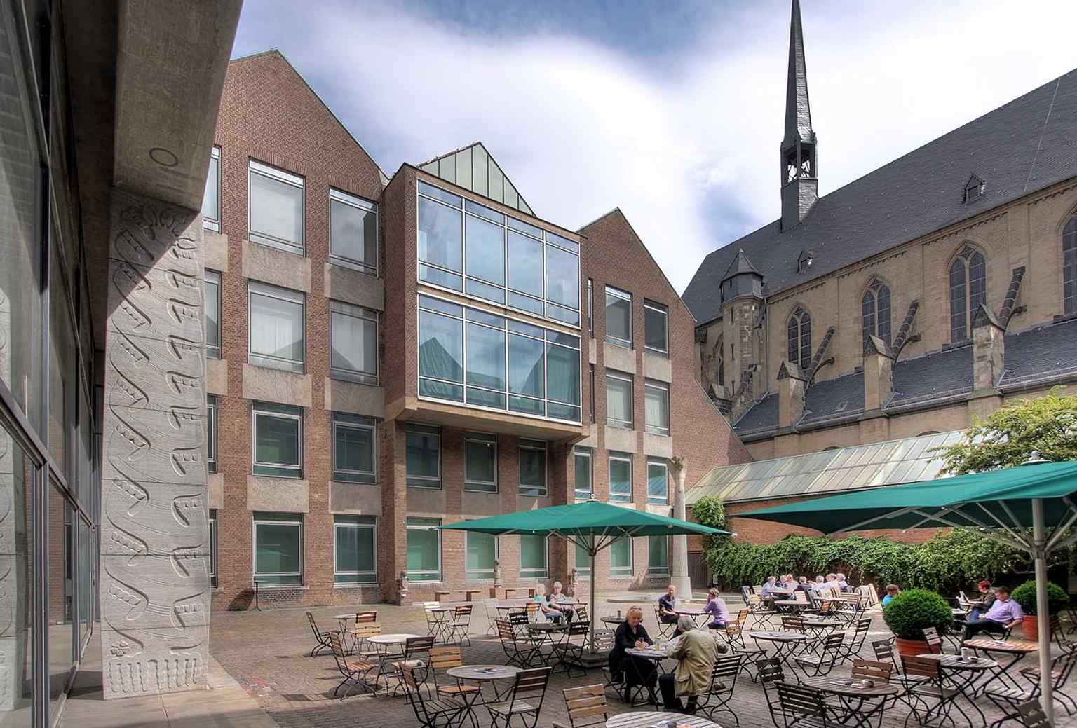 The quadratic inner courtyard of the museum, which replicates the basic form of the former Minorite cloister. The glazed wall on the north side, mentioned in the text, serves as a 'shop window' for the museum.