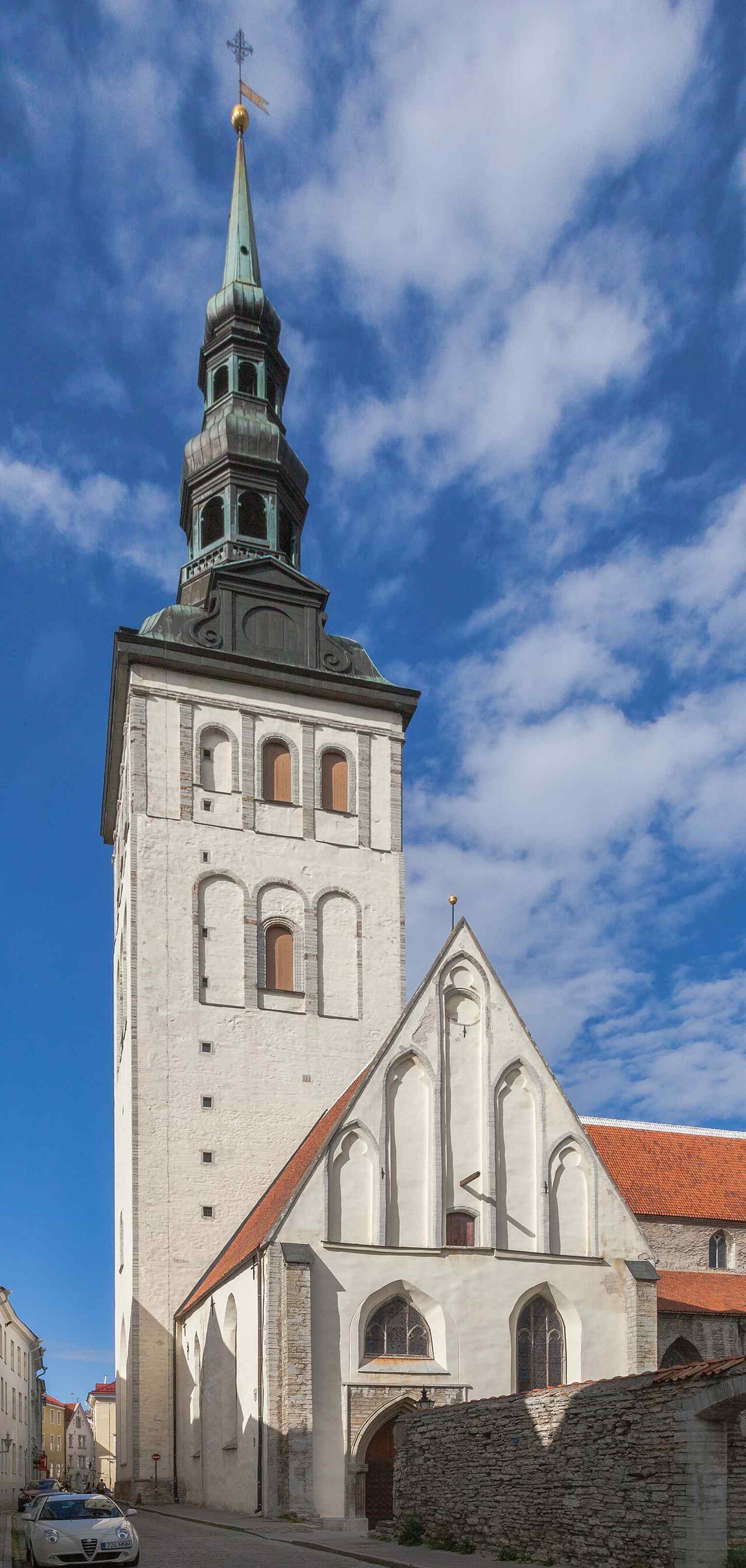 A close exterior view that helps show the church’s Gothic massing and tall brick tower above the old city streets.