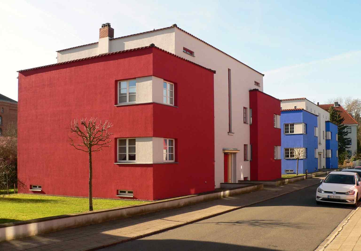 A side view of one of the red-accented houses, which contain three-room apartments of 85 m² and exemplify the settlement's bold use of color in architecture.
