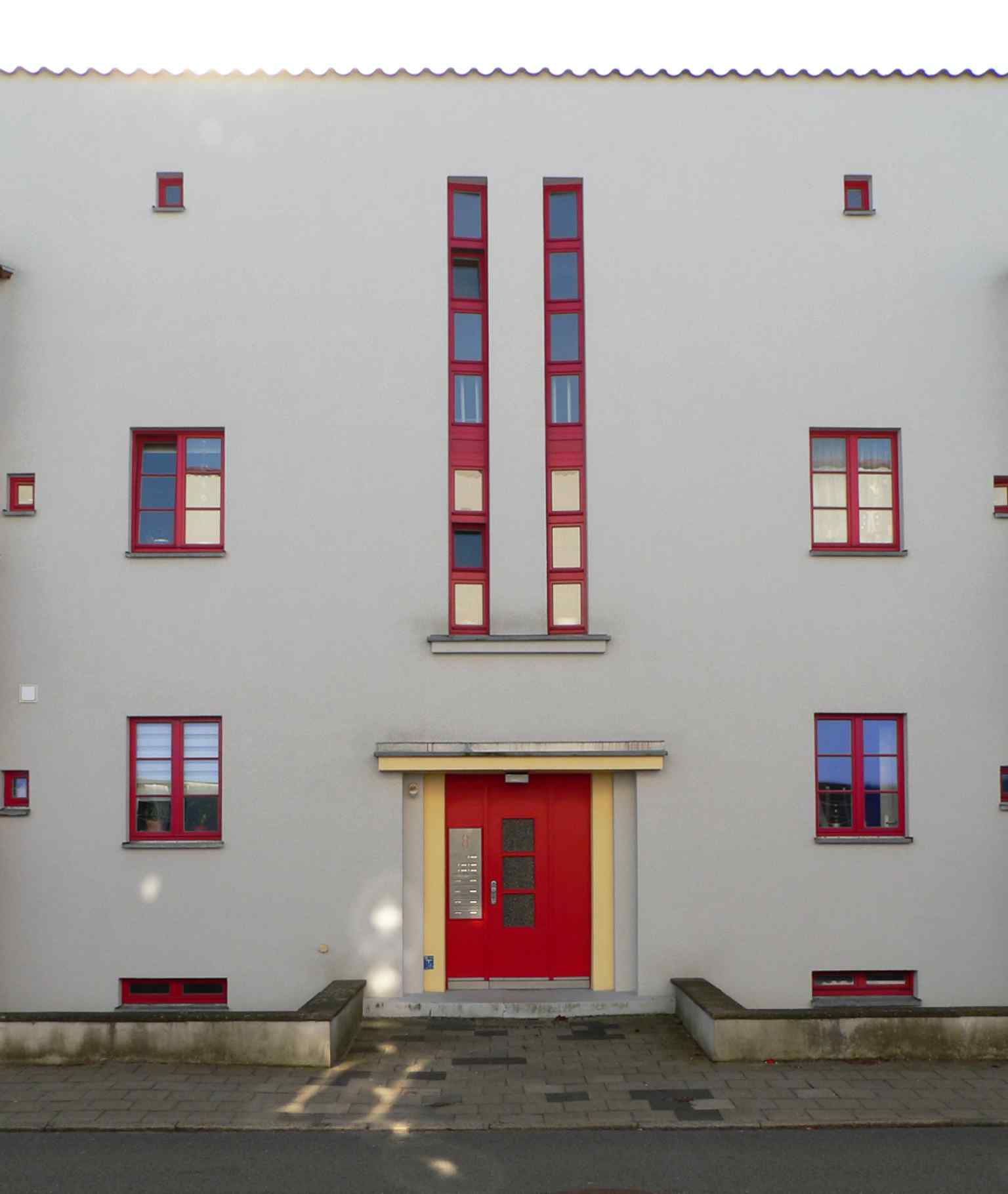 This entrance highlights the two-and-a-half-story white rectangular middle section, a key feature that visually anchors the two colored side cubes of the building.