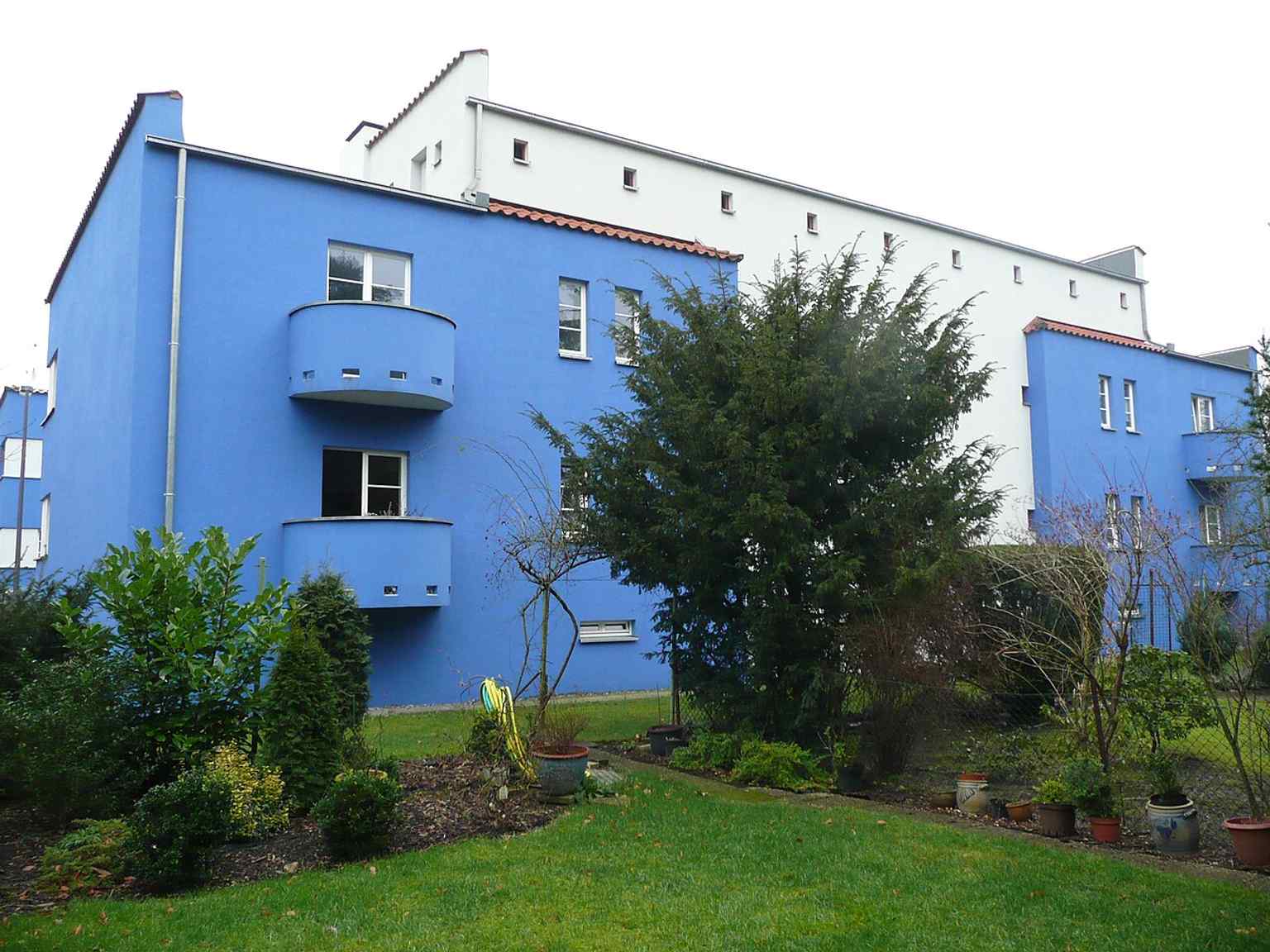 The rear facade reveals the small semi-circular balconies and the spacious 250 m² utility garden plots, which were originally provided for residents' self-sufficiency.