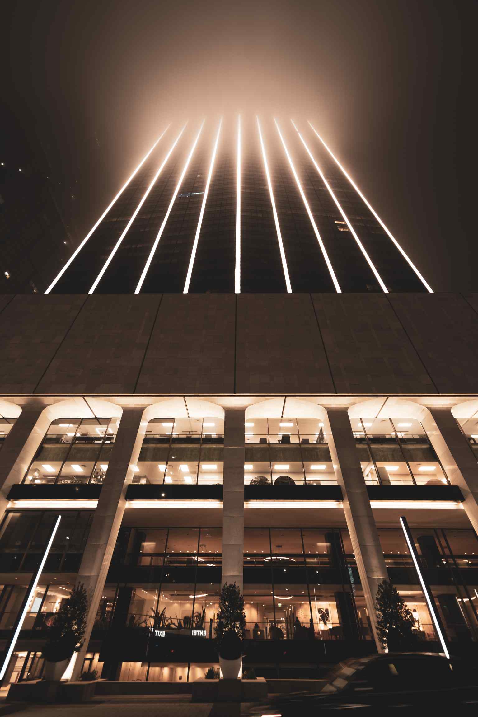 The tower illuminated at night, showcasing the striking dark gray glass and white vertical columns that locals joked resembled a wealthy banker's pinstriped suit.