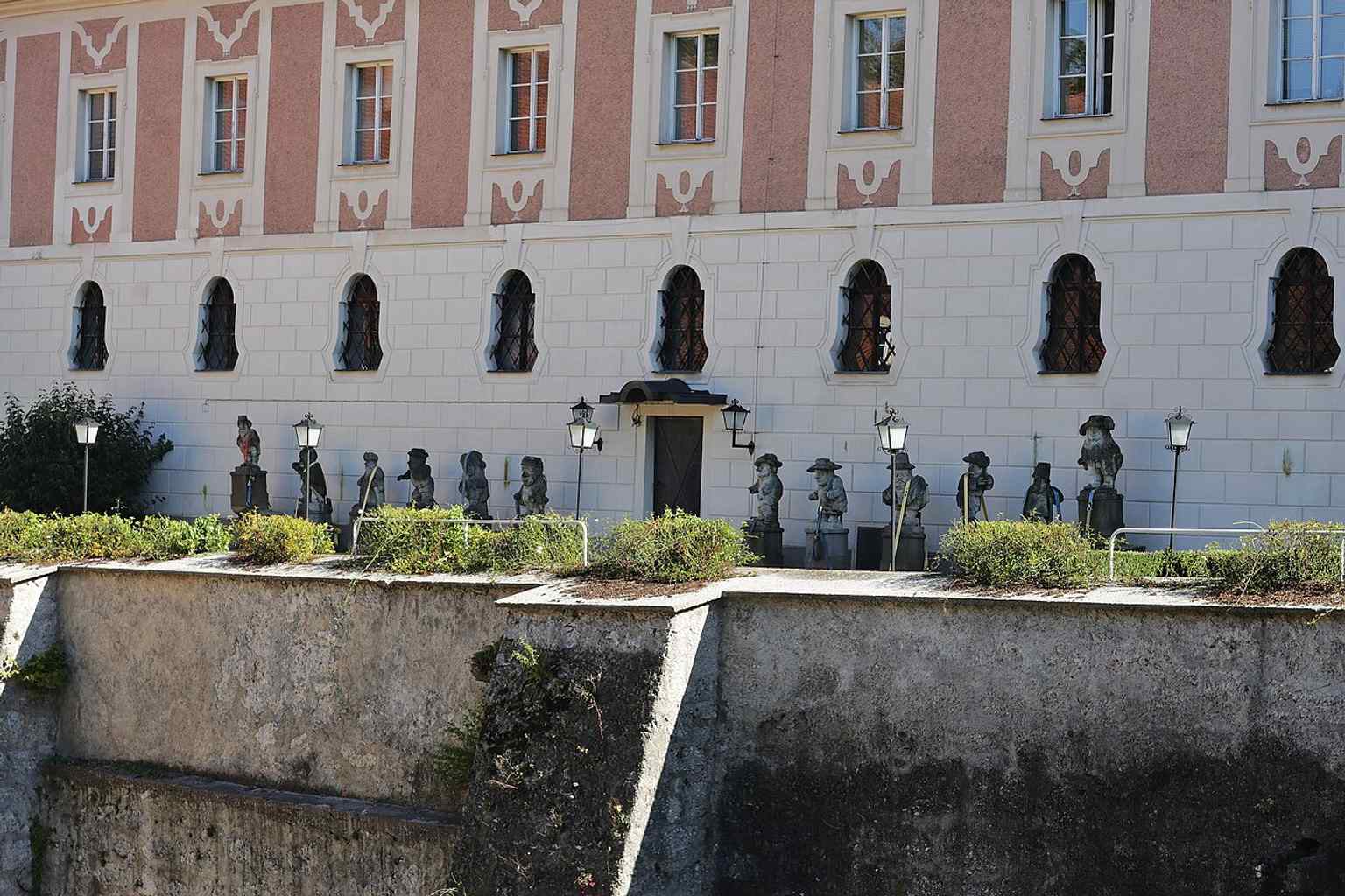 The barbacane and bridge passage show the surviving medieval defenses beneath the baroque castle complex.
