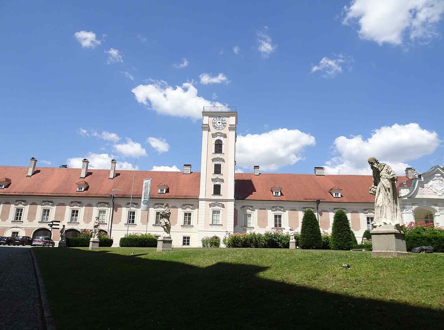 Baroque dwarf figures waiting beside the west facade — a reminder that the famous Zwergengarten pieces were moved here during courtyard restoration.