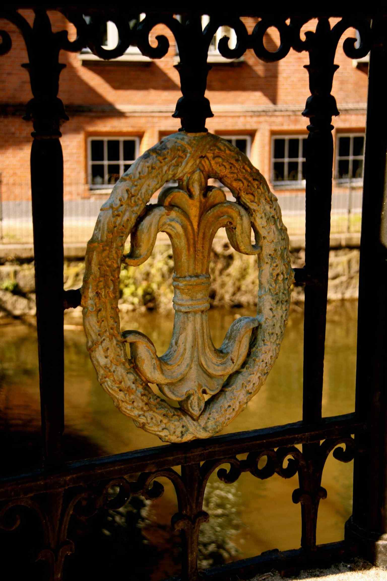 The Odense fleur-de-lis on Frederiksbroen’s ironwork, a close detail of the bridge’s characteristic cast-iron railing.
