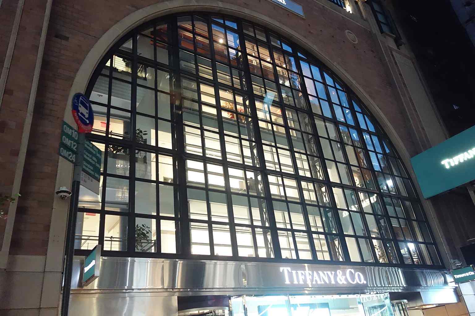 A street-level view of the Tiffany & Co. corner building at 57th Street and Fifth Avenue, showing the neighboring storefronts around the flagship.
