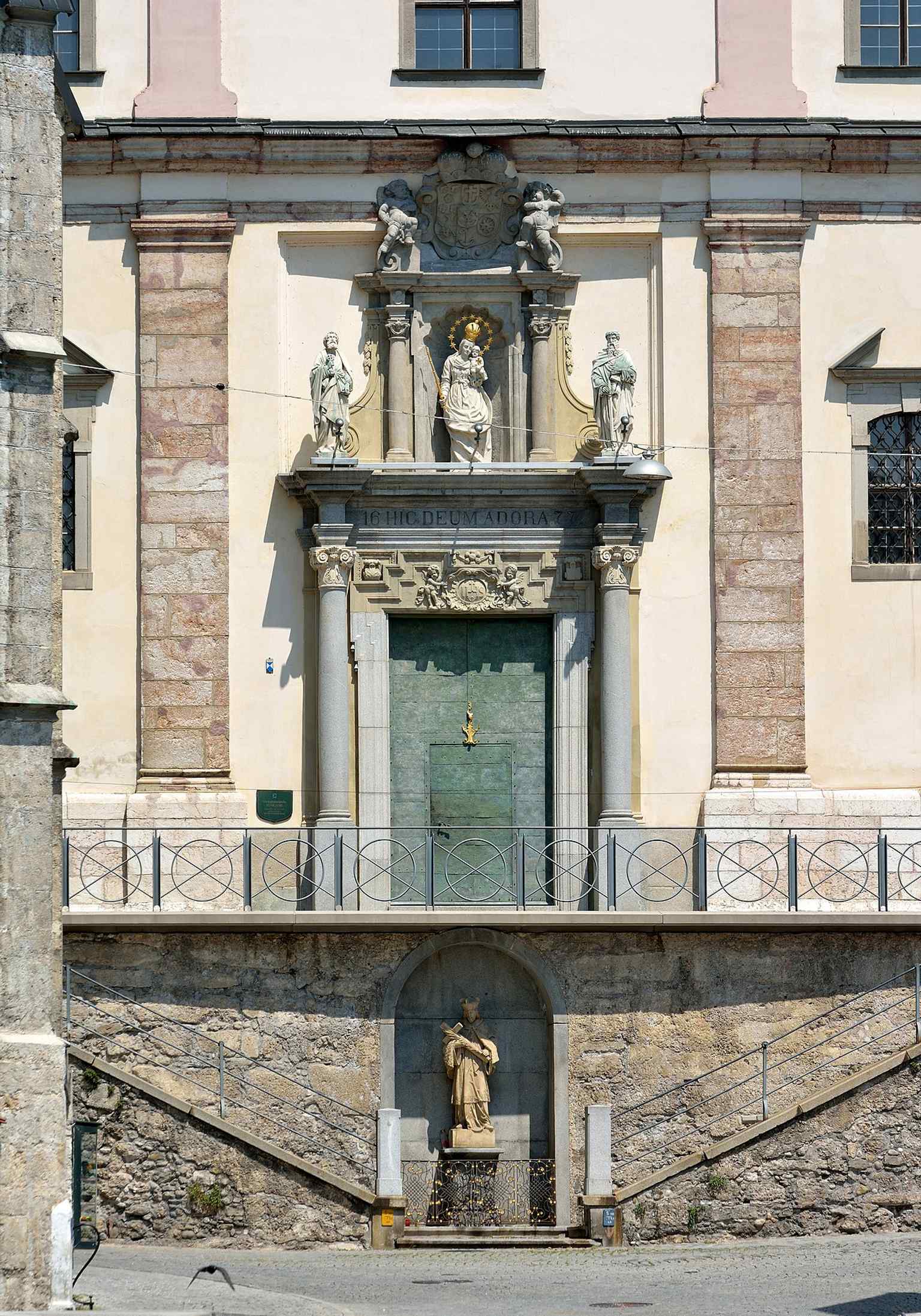 The 1677 portal with its monumental inscription HIC DEUM ADORA — a key Baroque entrance detail of the former Jesuit church.