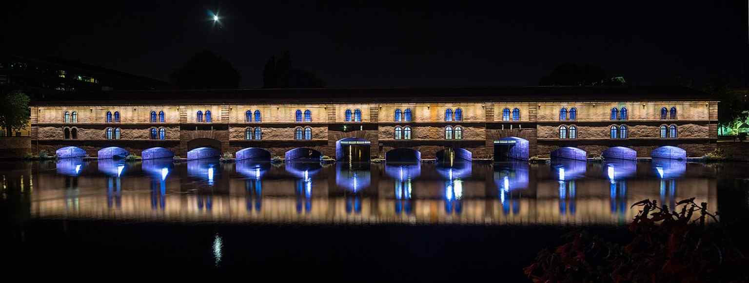 The Vauban Dam lit at night, matching its modern life as a public terrace since the military use ended.