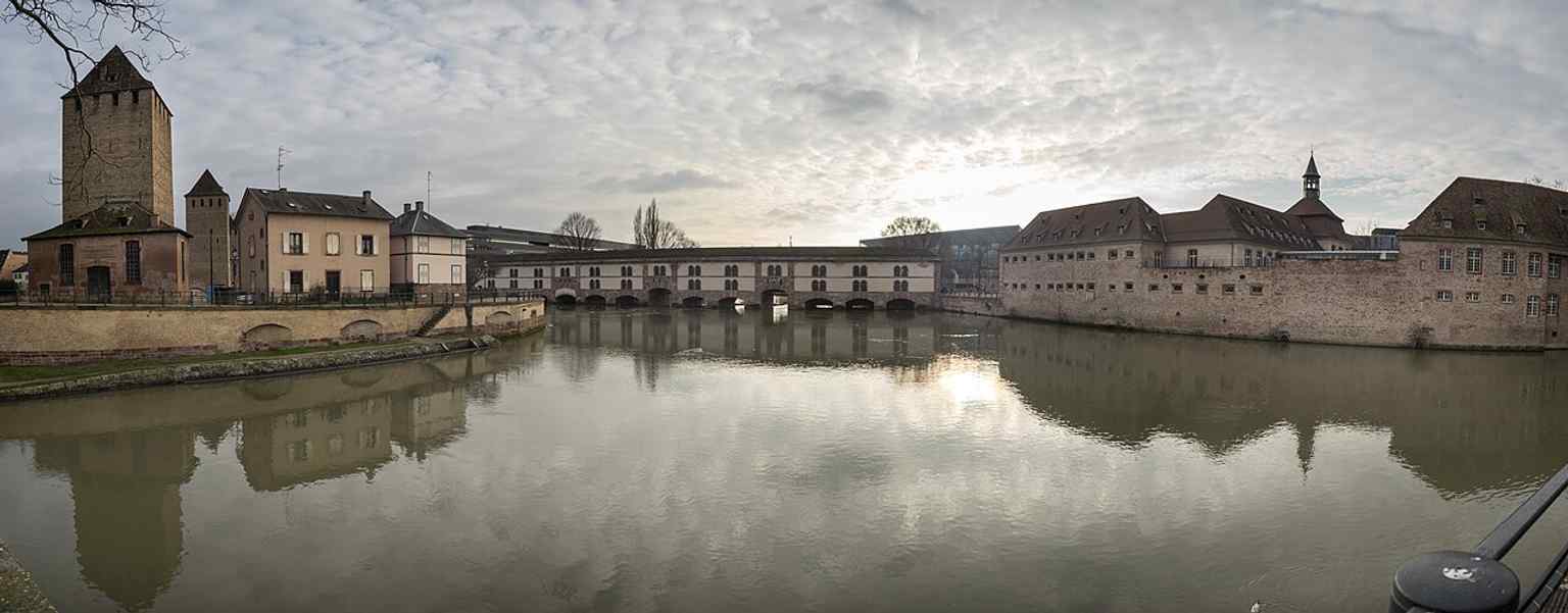 A wide panoramic view that makes the dam’s bridge-like form and its position beside Petite France easy to understand.