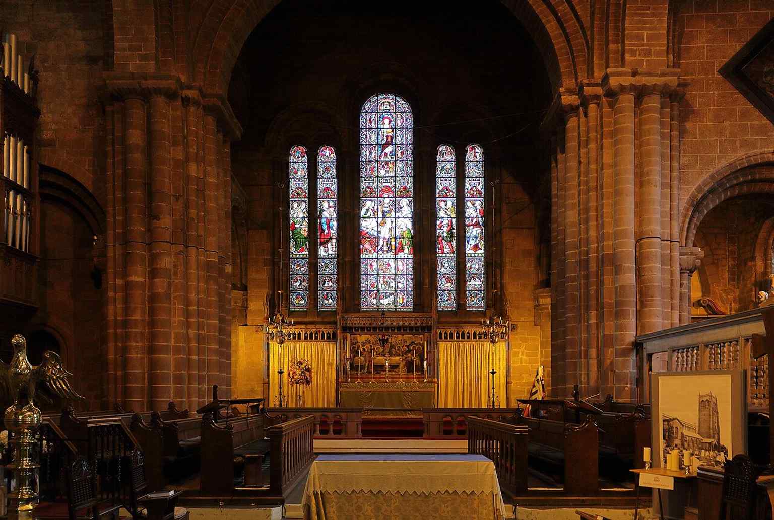 The chancel with altar and east window, highlighting the restored liturgical east end inside a church whose original eastern arm is now largely ruined.