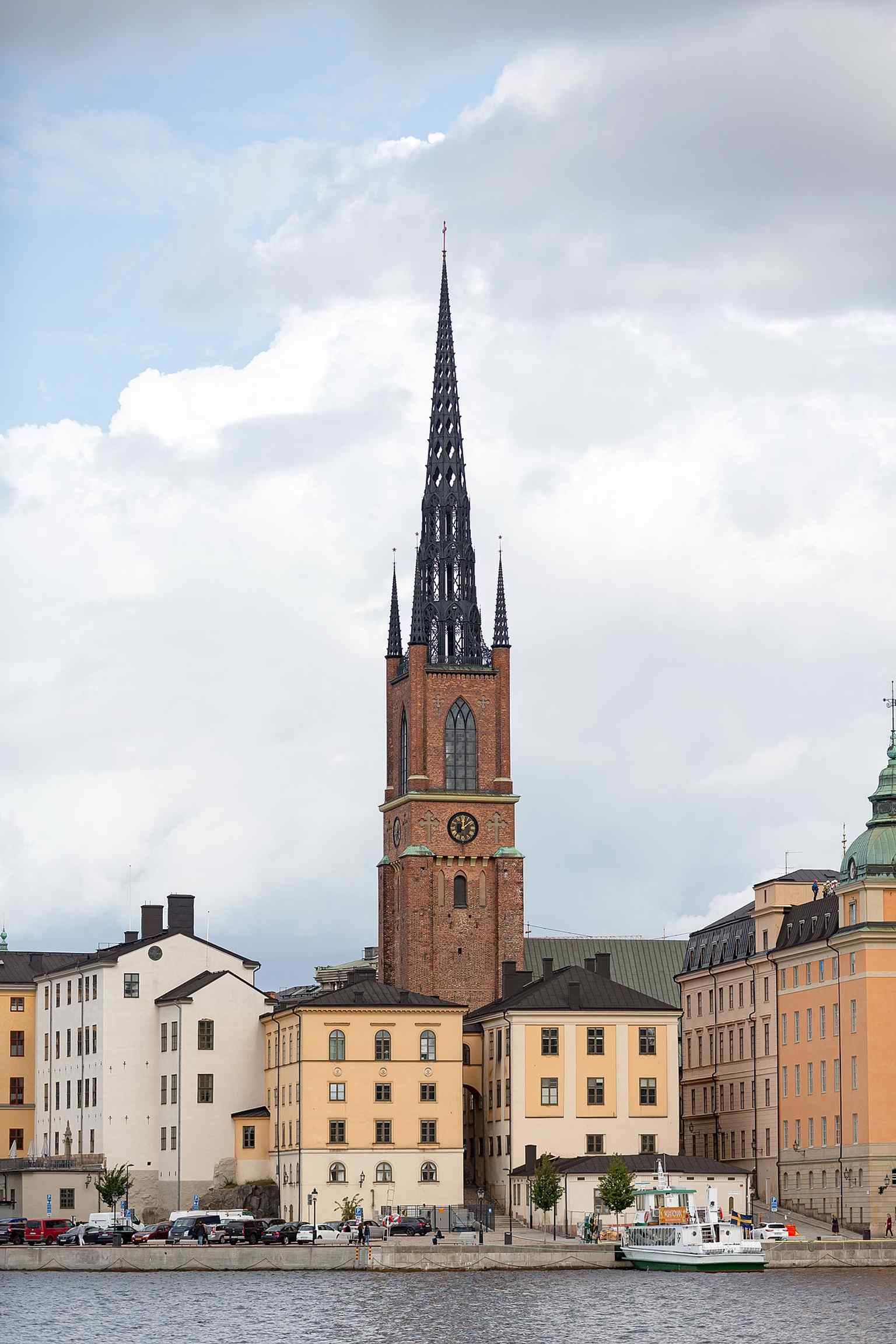 A wide view across the water toward Riddarholmskyrkan, emphasizing its dramatic island setting in central Stockholm.