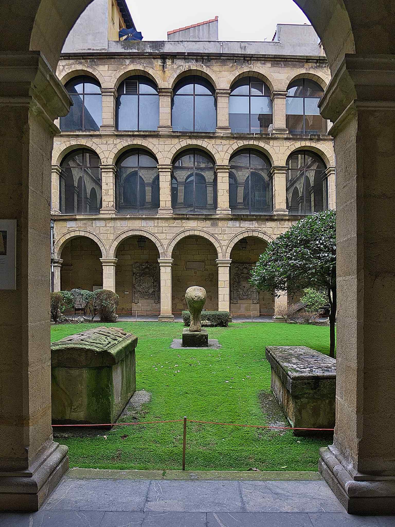 Medieval sarcophagi on the cloister floor — a reminder that the museum grew out of the old San Andrés college complex in Bilbao.