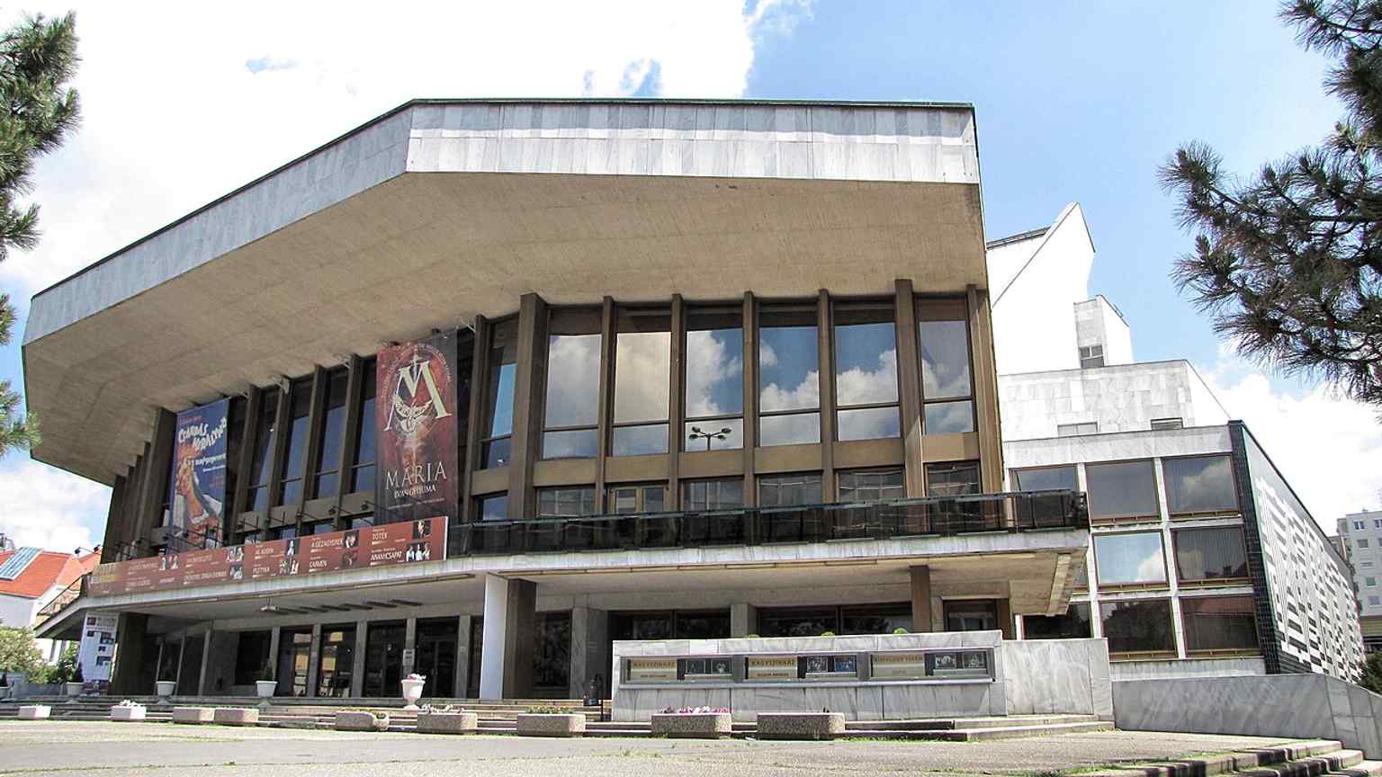 A clear wide exterior of the theatre, matching the 1978 building that replaced the old Radó Island stone theatre.