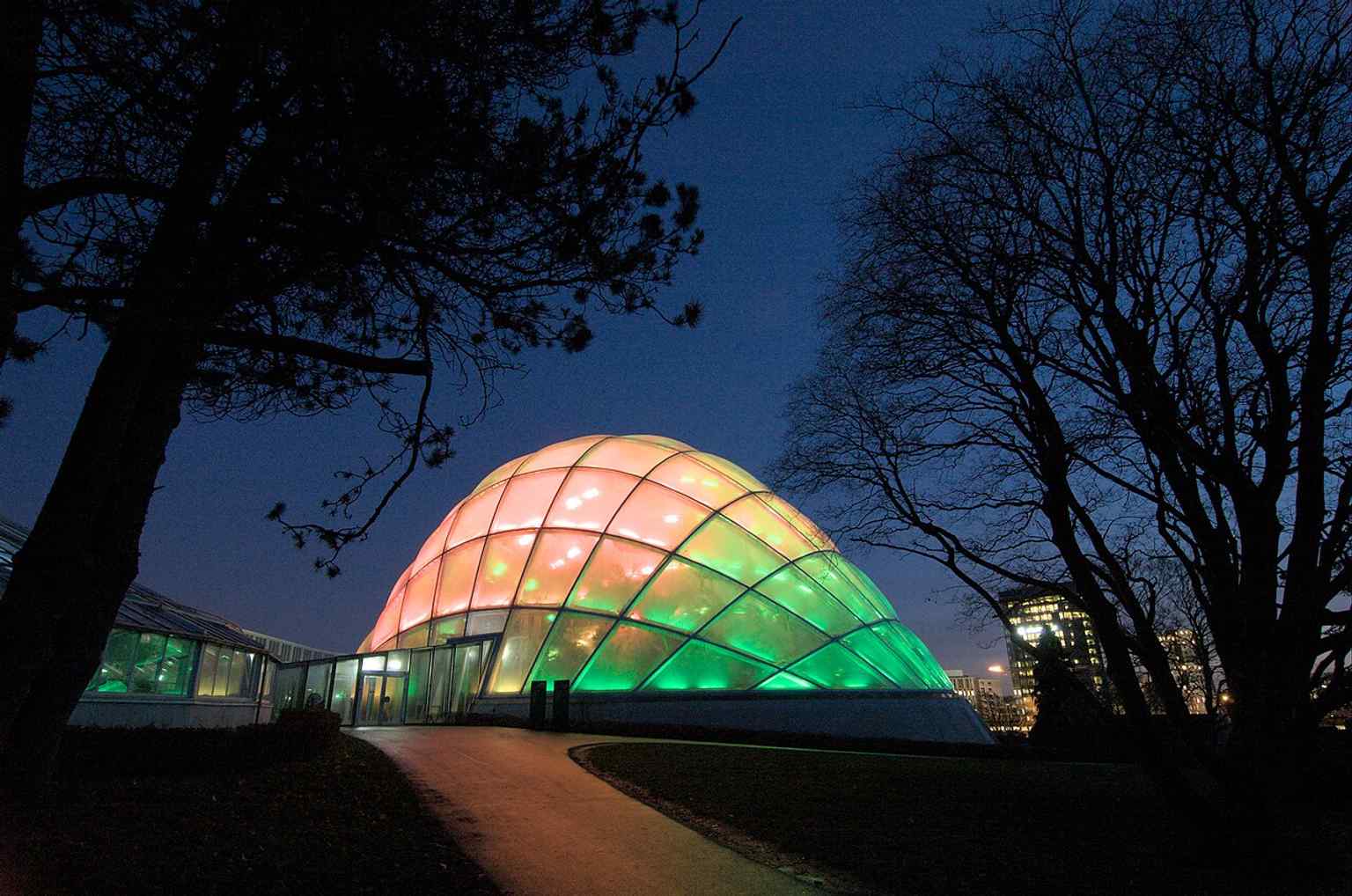 The illuminated conservatory in 2017, showing the greenhouse complex that brings together plants from different climate zones.