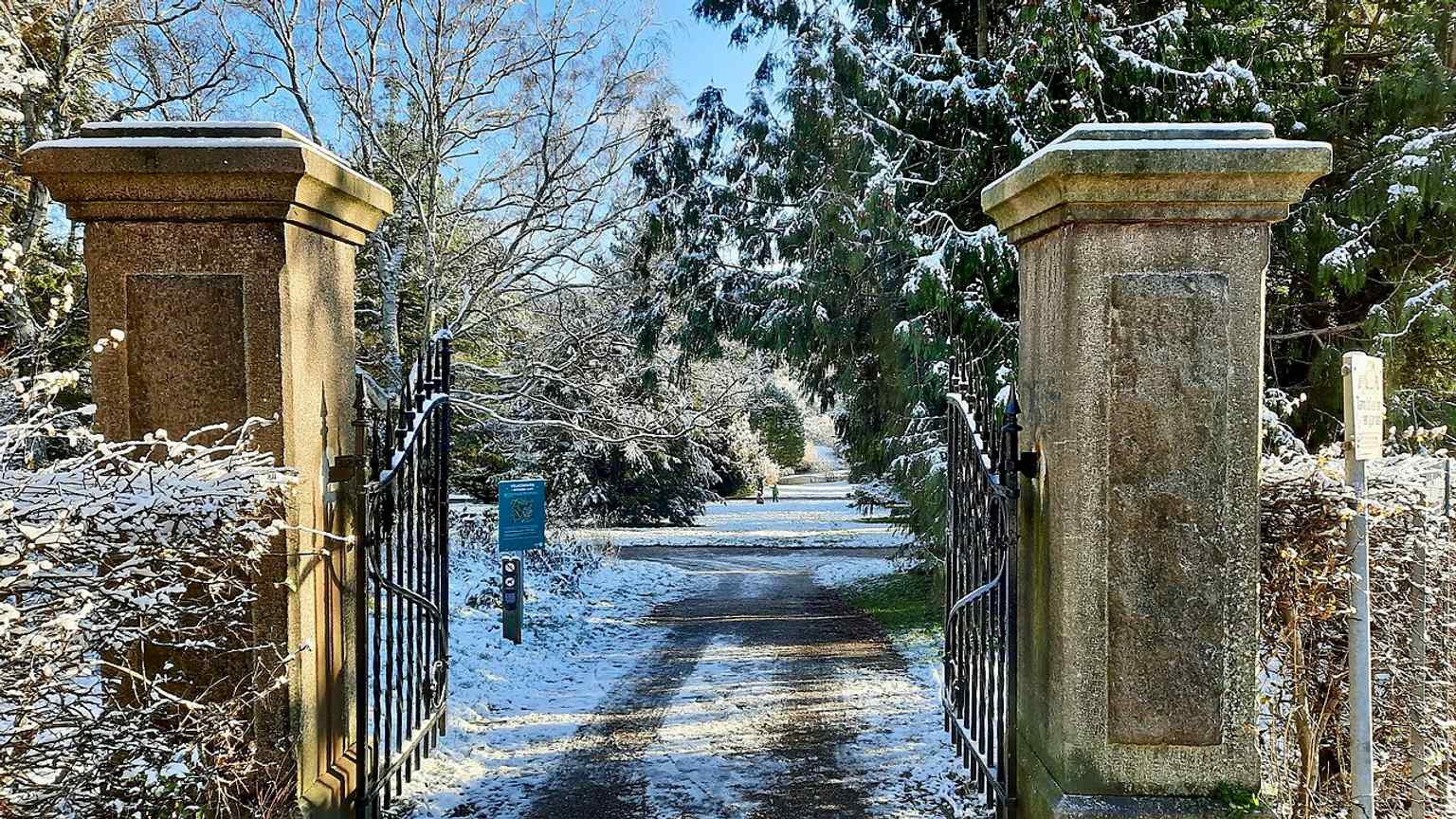 The main entrance on Eugen Warmings Vej, with old stone pillars and open gates leading into the park that borders Den Gamle By.