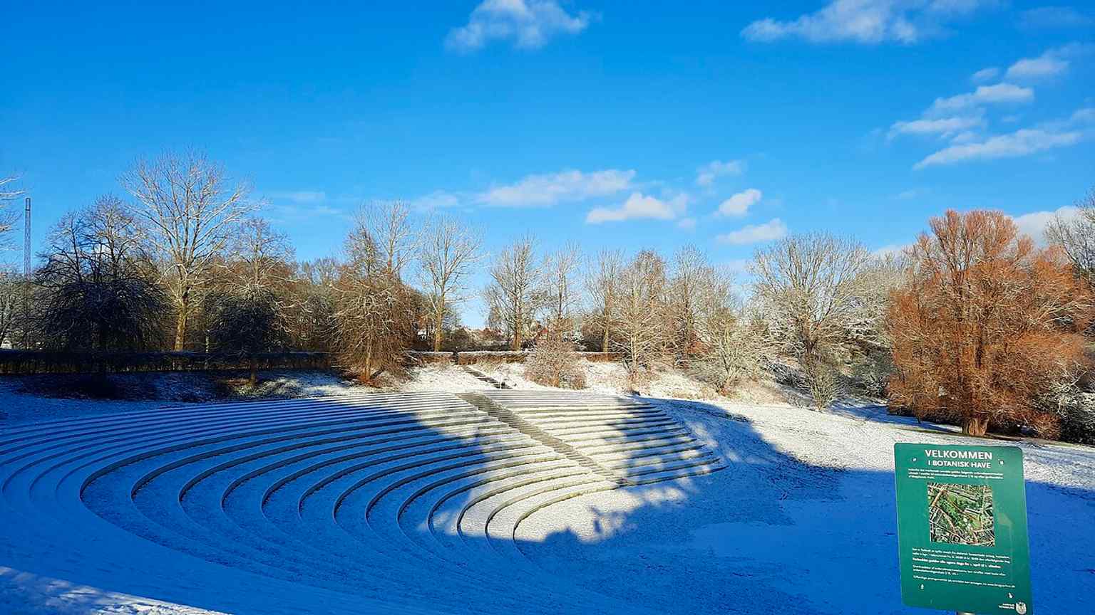 A snowy winter view with the garden sign visible, capturing the park’s free-access recreational character as well as its landscaped grounds.