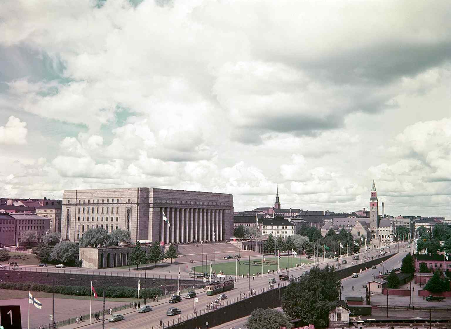 Olympic-era flag decorations on Mannerheimintie place Parliament House in a moment of national celebration in the early 1950s.