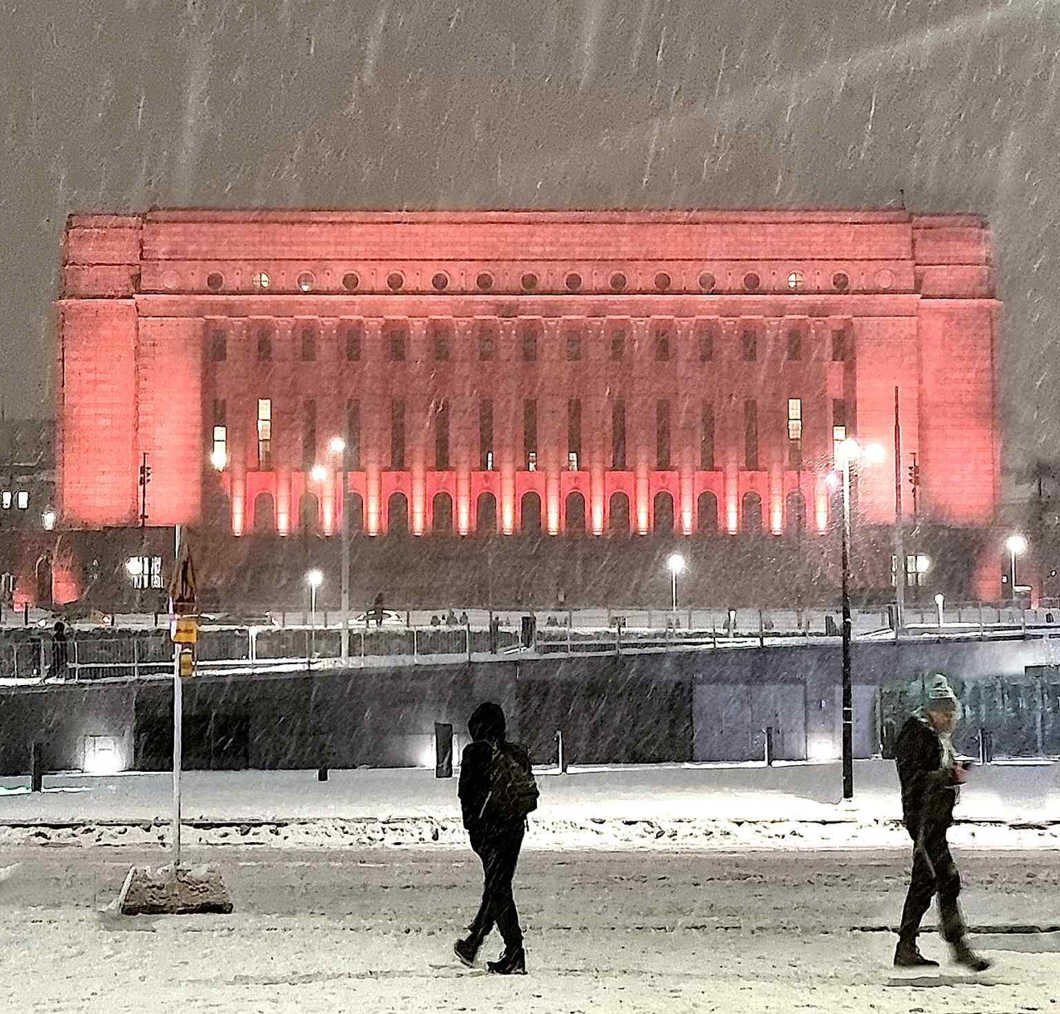 The building in red light creates a dramatic modern portrait of the parliament, a useful contrast to its restrained classical facade.