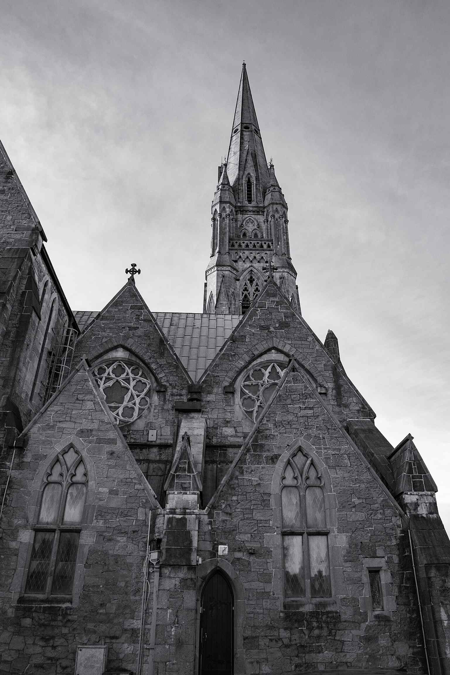 A dynamic exterior perspective of St. John's Cathedral, highlighting the impressive height of its spire, which was constructed between 1879 and 1883 by Thomas Byrne.