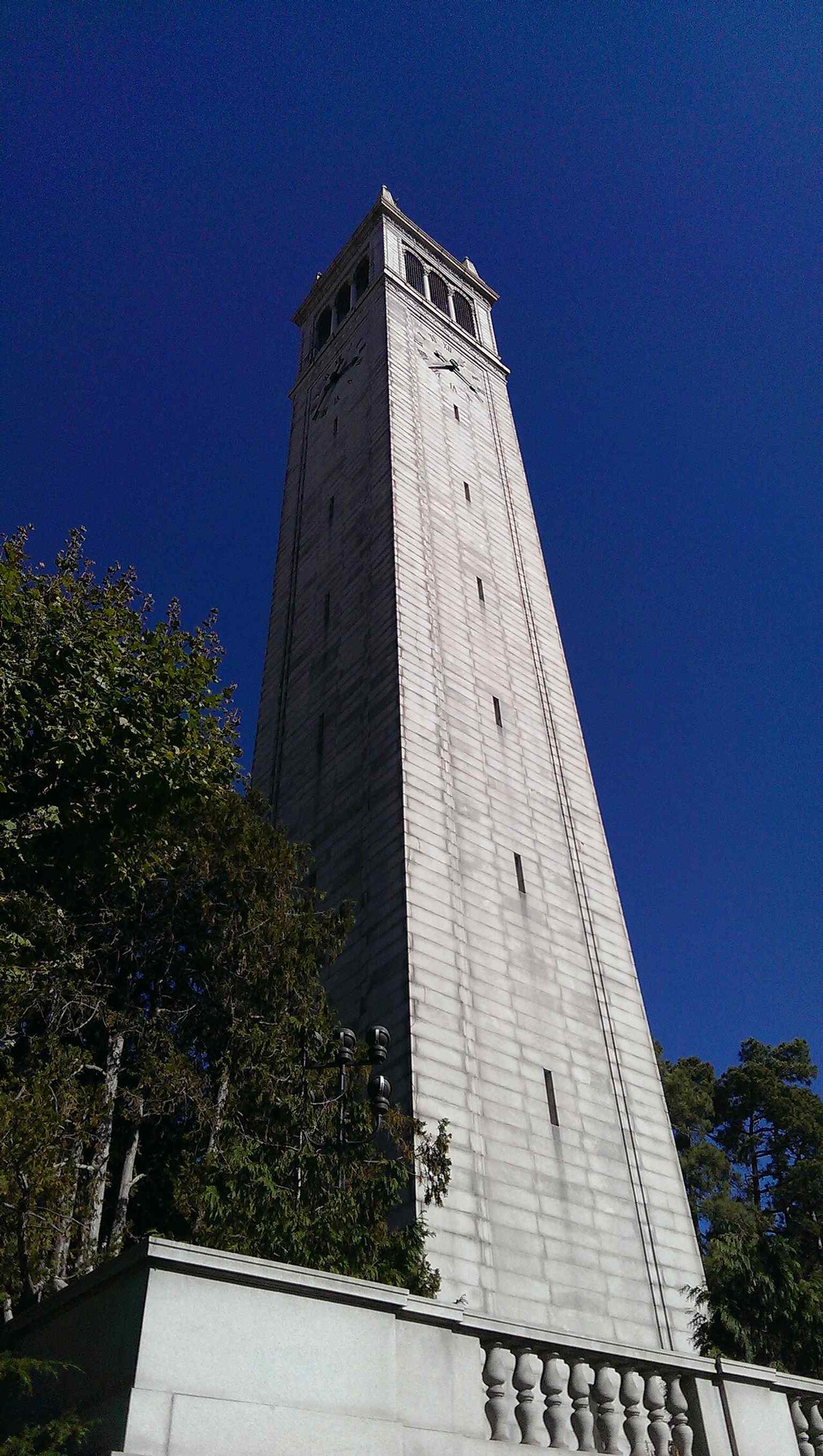 A close view of the tower’s stonework and clocks, highlighting the four-faced bell-and-clock design that made it a campus icon.