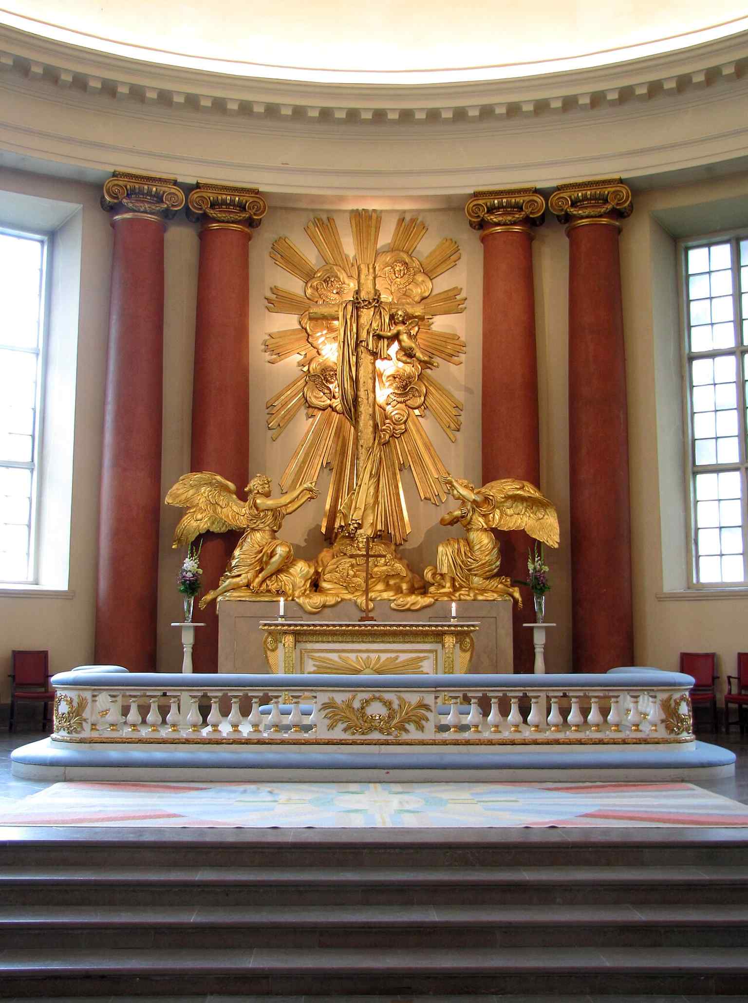 The altarpiece, still in use today, features Baroque angelic figures sculpted in 1752 by Jacques Adrien Masreliez and salvaged from the 1802 fire.