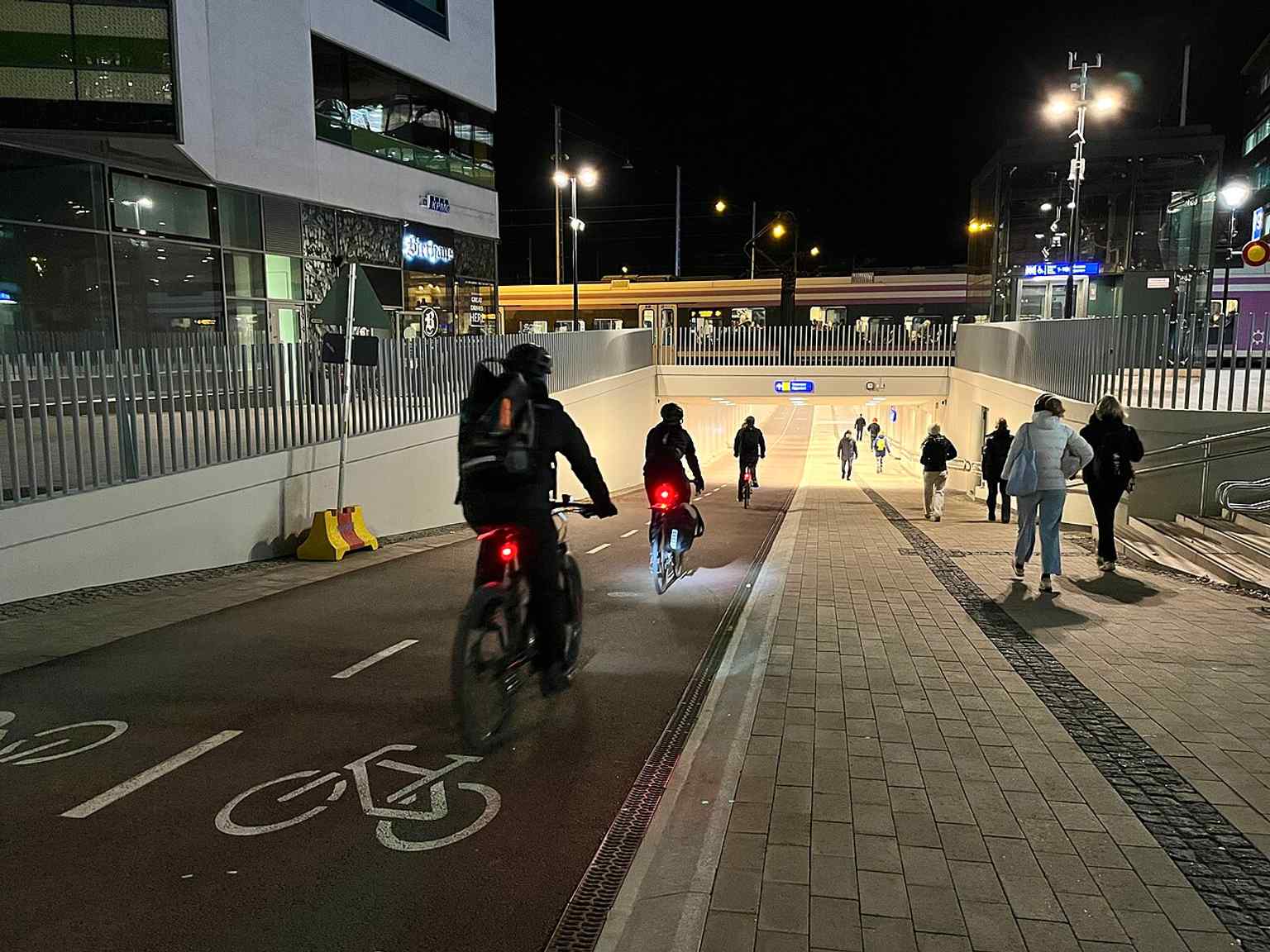 The tunnel’s nighttime interior in use, highlighting the dedicated pedestrian and bicycle route linking the station area to the city cycling network.