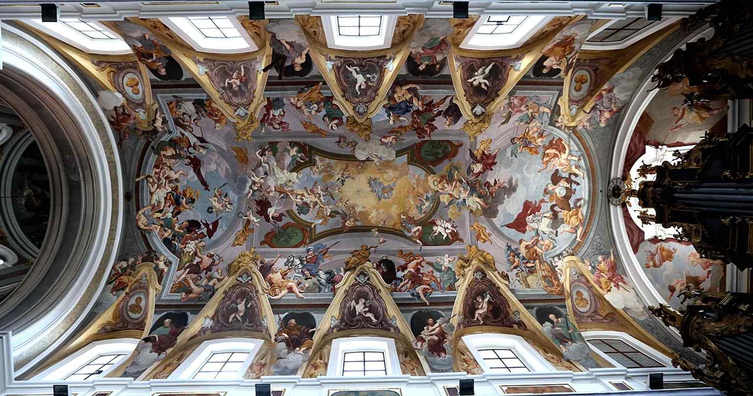 The opulent interior is adorned with significant Baroque elements, including the altar angels by the brothers Paolo and Giuseppe Groppelli and Francesco Robba, contributing to the 'Gesamtkunstwerk' (total work of art).