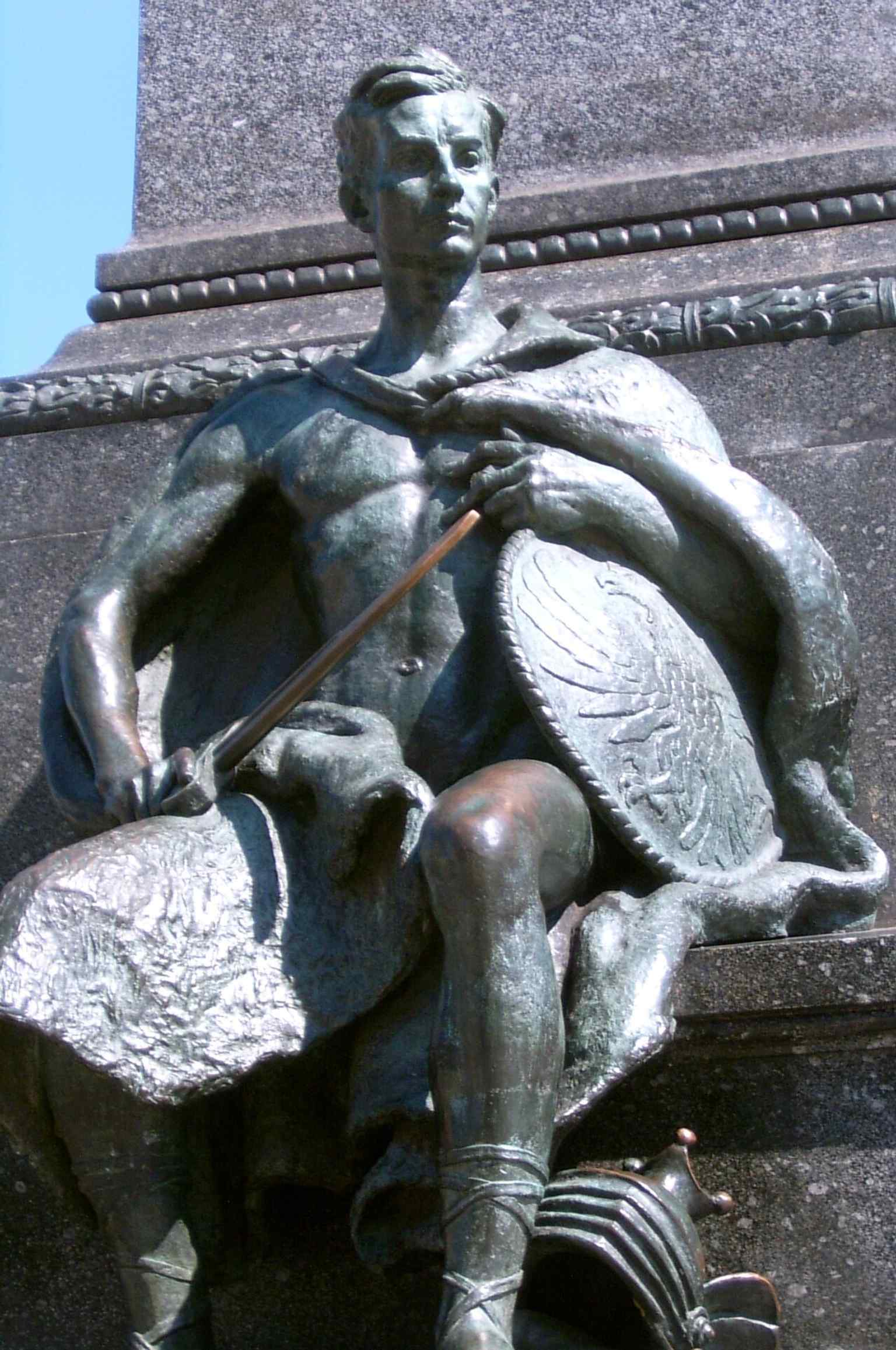 A closer look at the sculptural base, where the seated allegorical figures help tell the monument’s story beyond the poet himself.