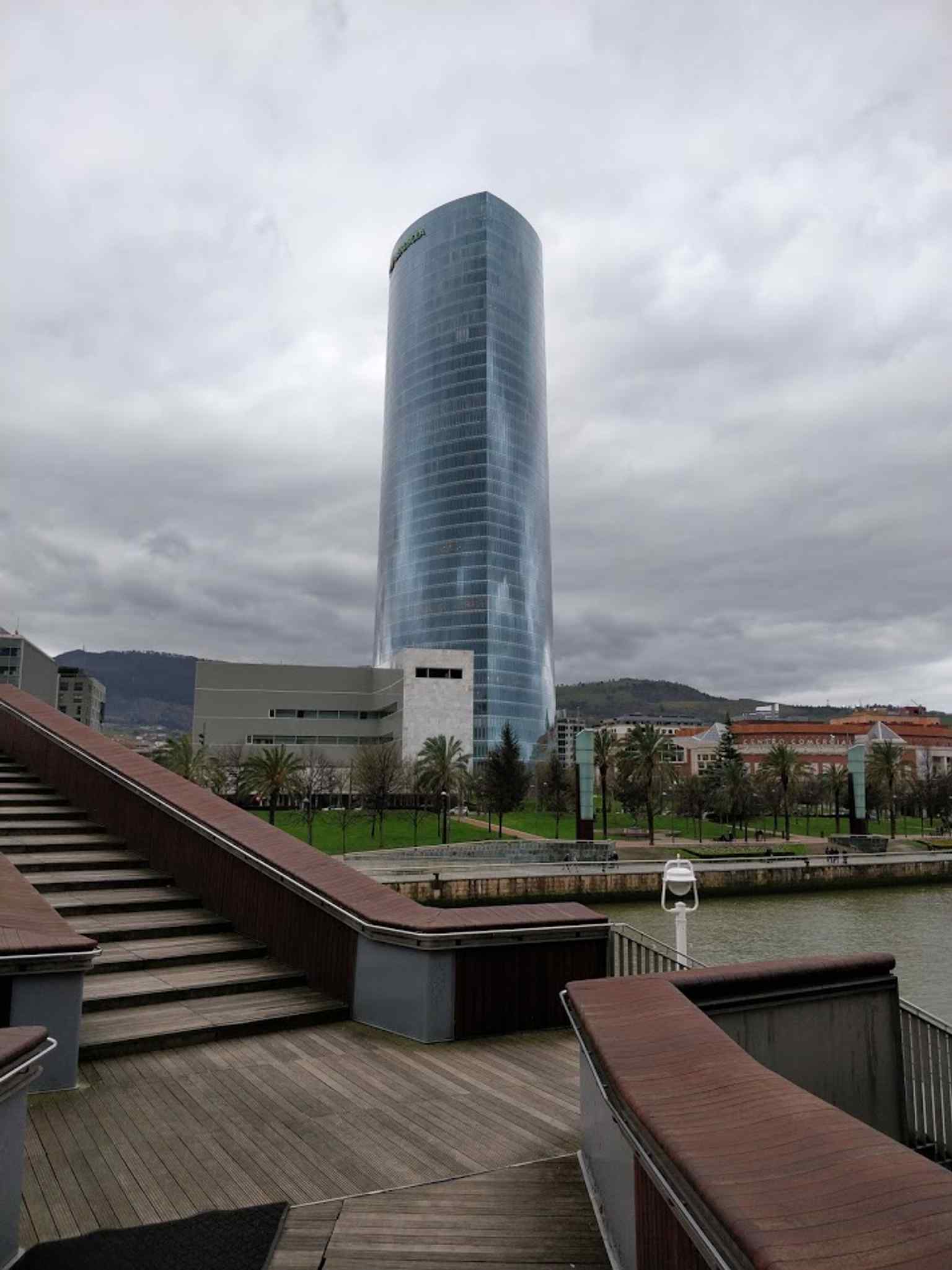 Seen from the Pedro Arrupe footbridge, this angle places the tower in its Abandoibarra riverside setting beside the Nervión.