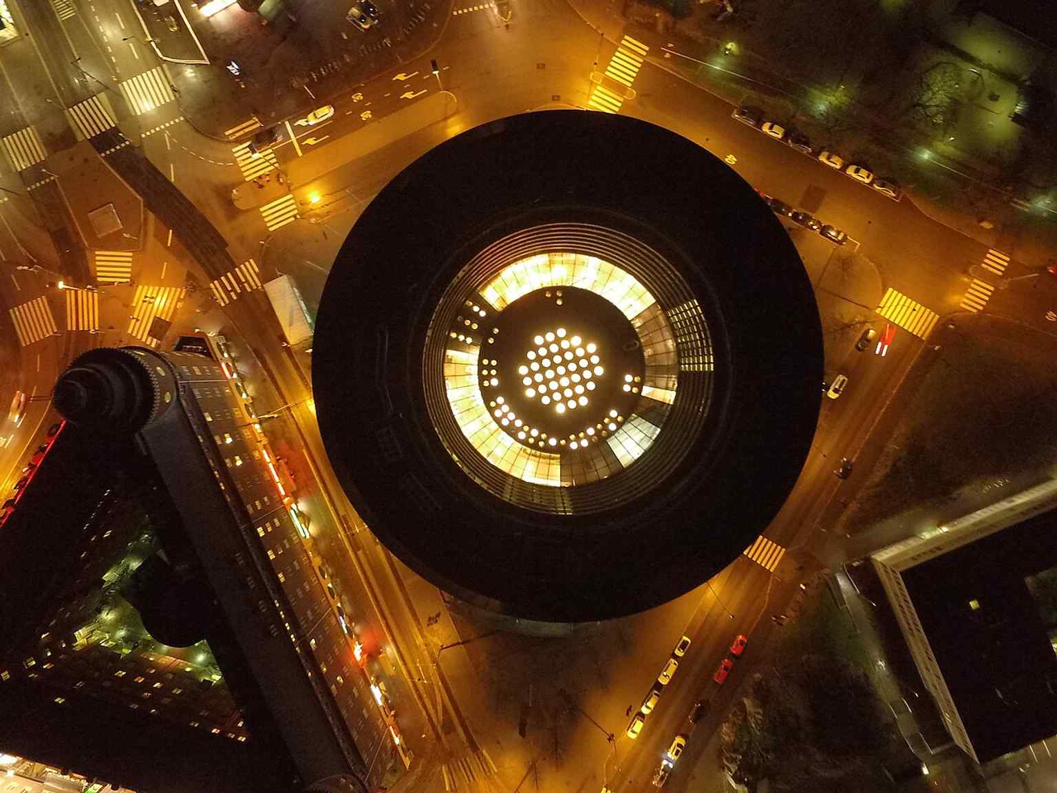 Night aerial of Ympyrätalo, showing the building’s distinctive round mass that makes it look compact from the street despite its large size.