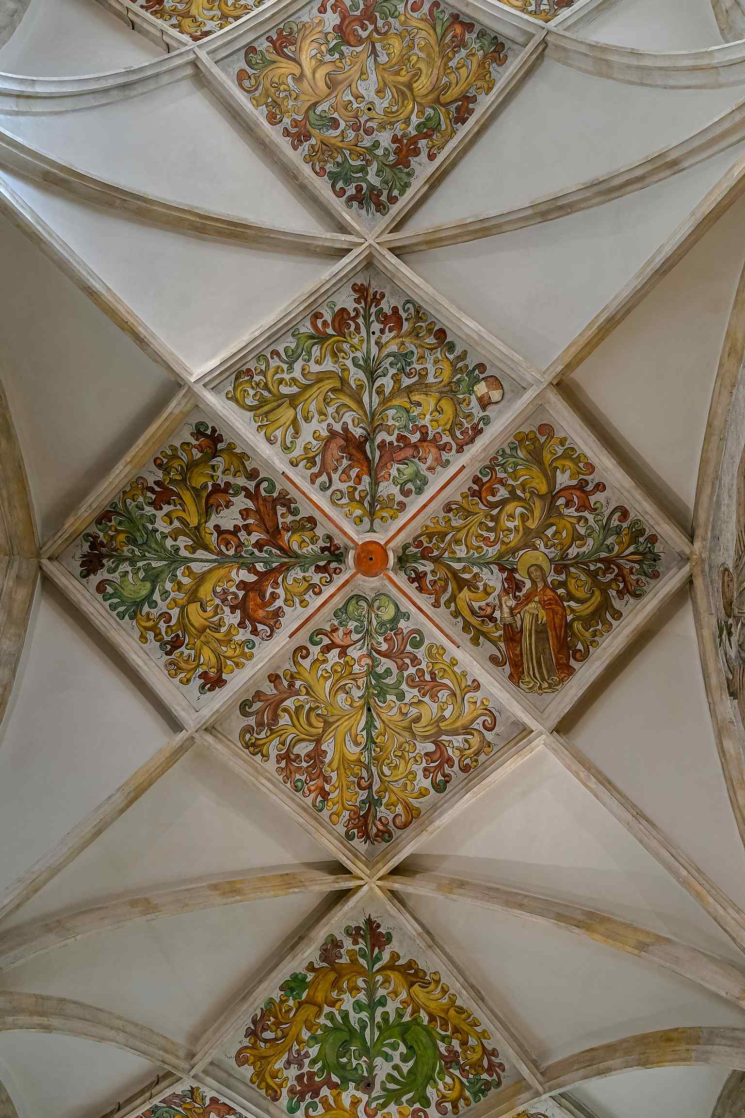 Late Gothic vault painting survives here: tendril and flower frescoes dated 1464 in the side aisle.
