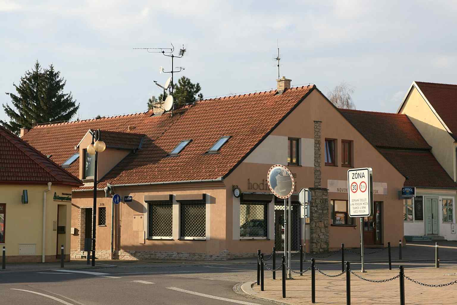 This modern view from Boženy Němcové street highlights the houses at the former site of the Hodinová brána, including a symbolic marker for the medieval city fortifications that once protected the town.
