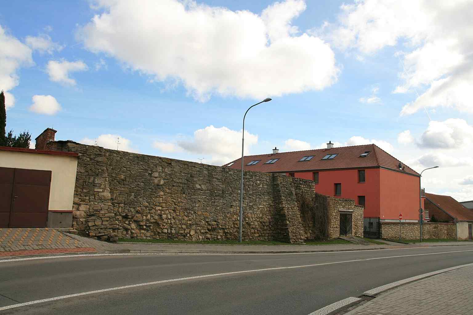 This wide shot showcases a well-preserved section of the medieval city walls in Kollárova Street, which forms part of the culturally protected western fortification line.