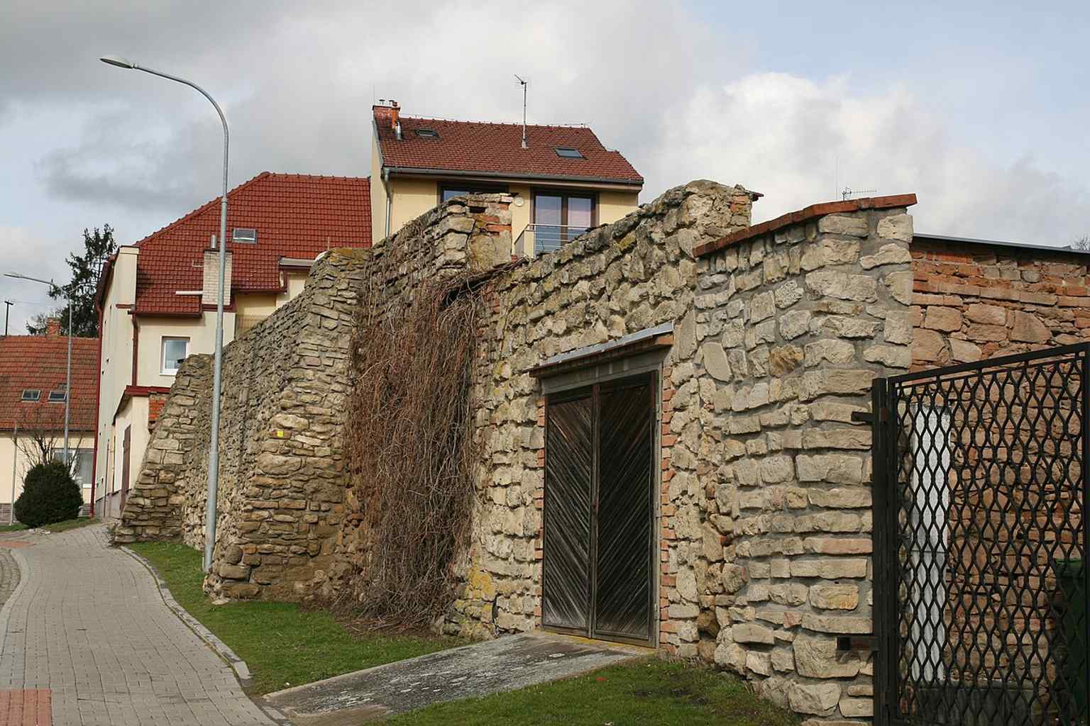 This view captures a section of the city walls from a higher vantage point near a residential building, providing a different perspective of the medieval fortifications in Kollárova Street.