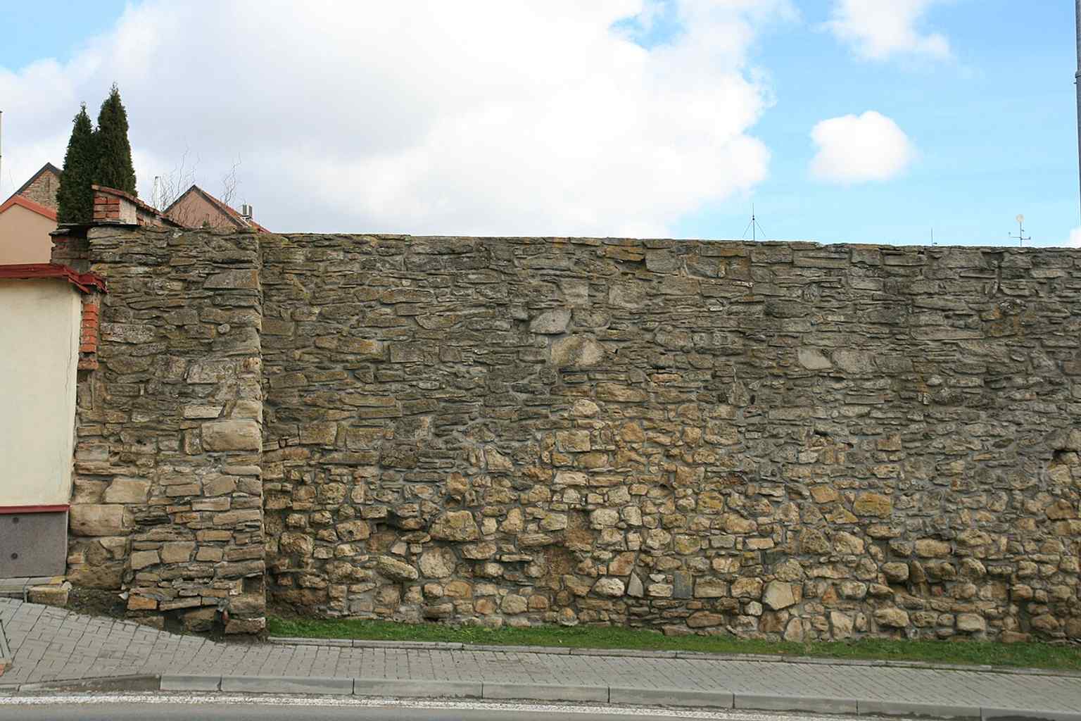 This image shows an end section of the medieval city wall in Kollárova street, featuring a prominent supporting pillar and the adjacent house, illustrating how the walls became integrated into the urban fabric.