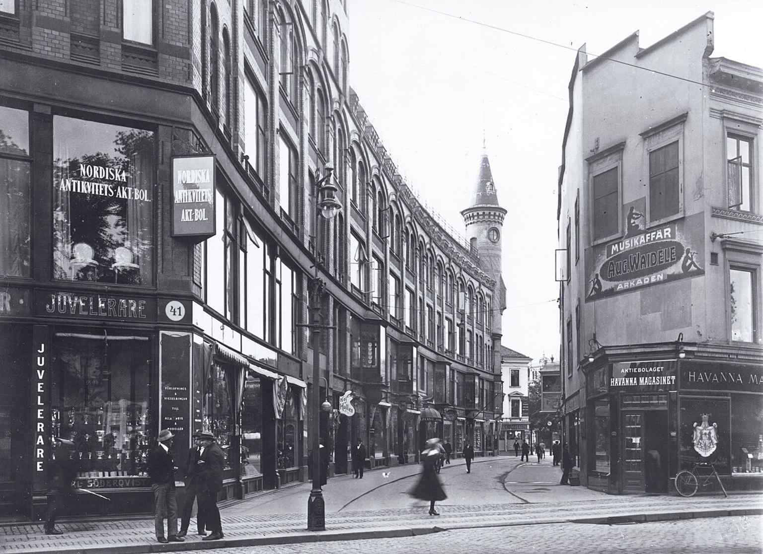 The original 'Arkaden' building in 1916, featuring the unique privately-owned street 'Arkadpassagen' that diagonally cut through the block, and the distinct brown-red brick architecture with turrets and towers.