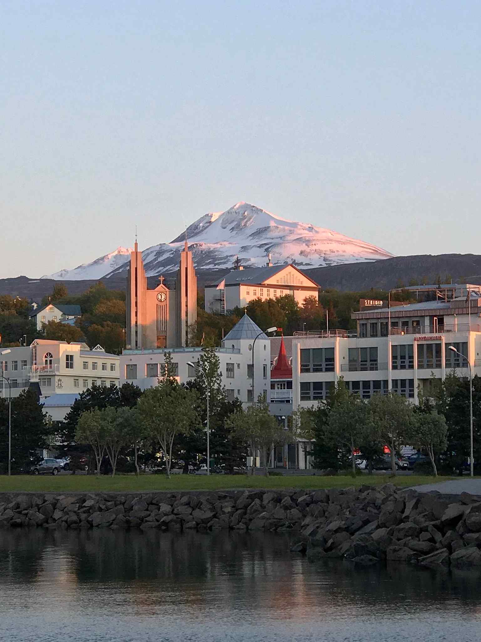 A broad city-and-church panorama with Mount Súlur in the background, placing Akureyrarkirkja in its dramatic northern Iceland setting.