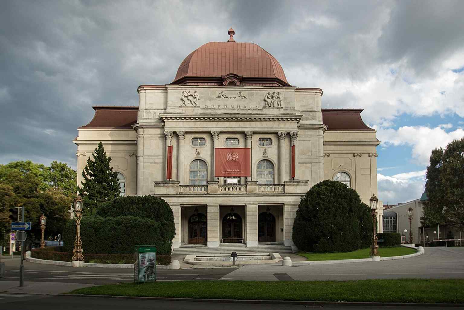 A broad exterior view that highlights the theatre’s monumental, historicist presence in the centre of Graz.