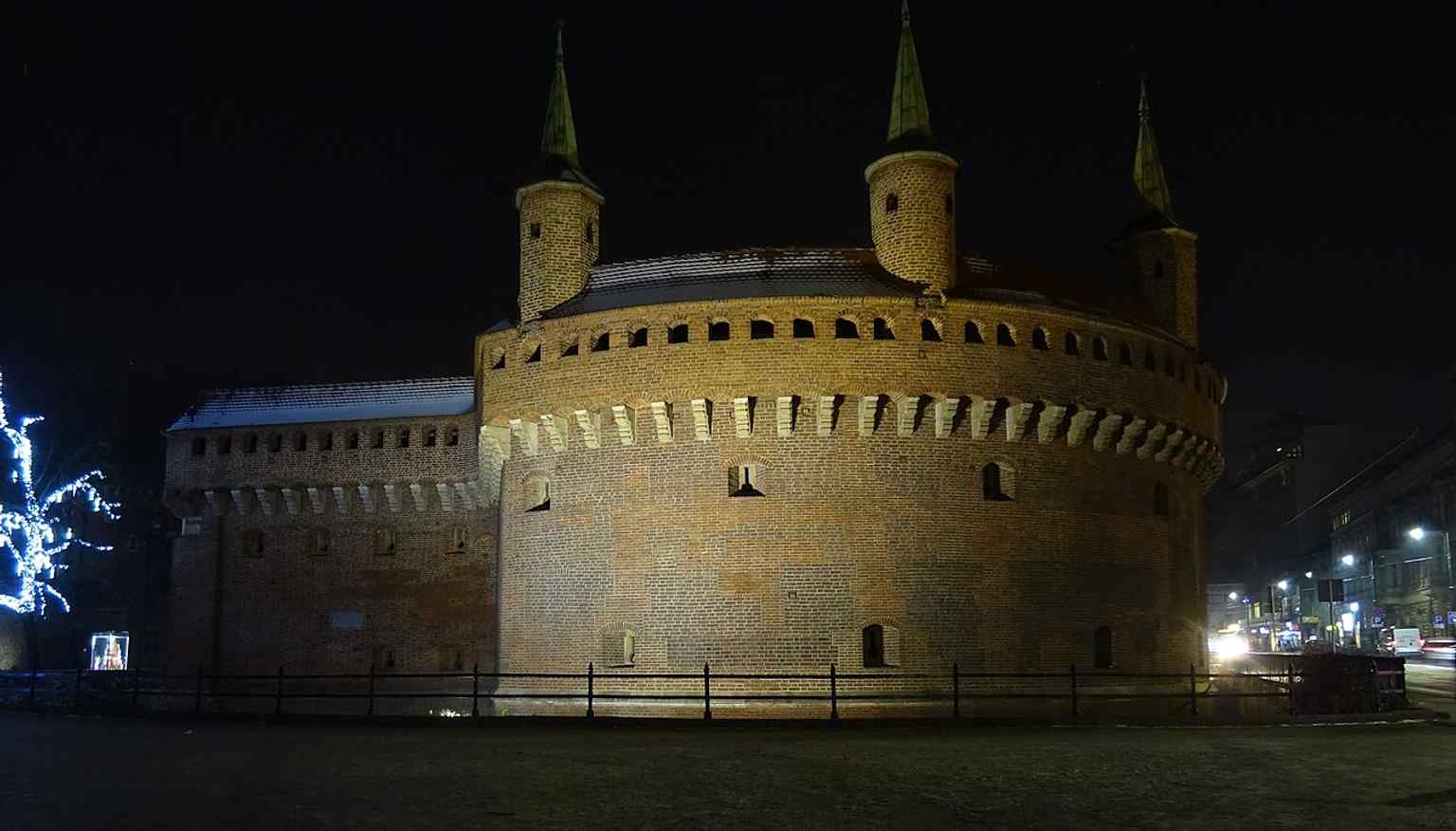 Night lighting transforms the Barbican into a dramatic silhouette, while still showing the massive round bastion that once faced attackers from the north.