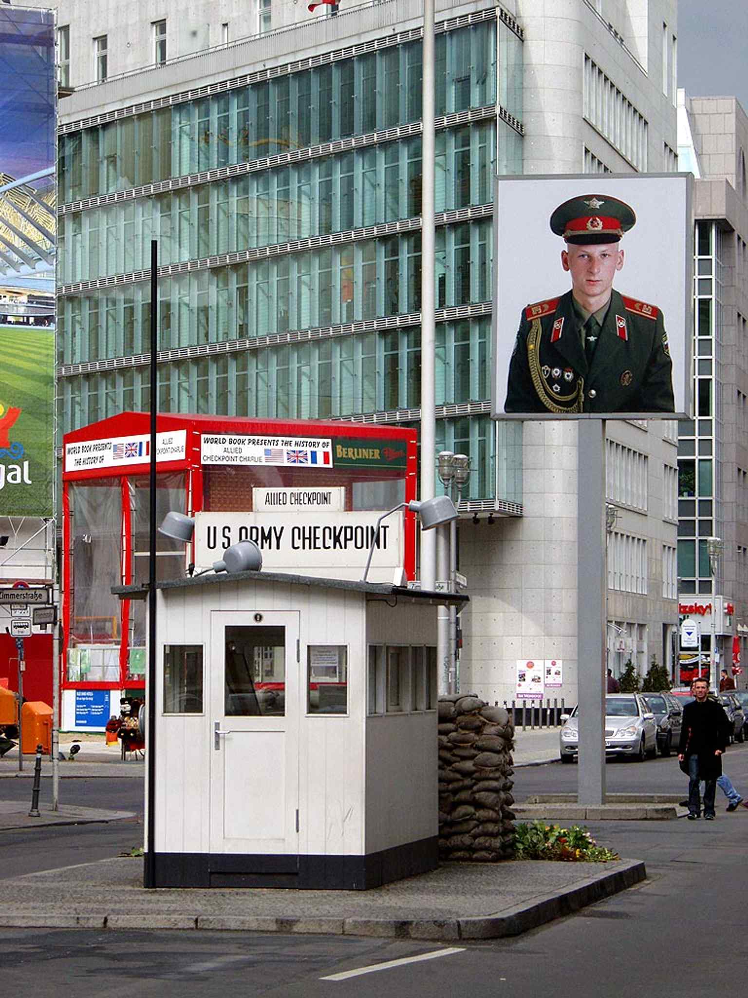 A 2004 memorial view at Checkpoint Charlie, tracing the former crossing line across Friedrichstraße with the border now marked for visitors.