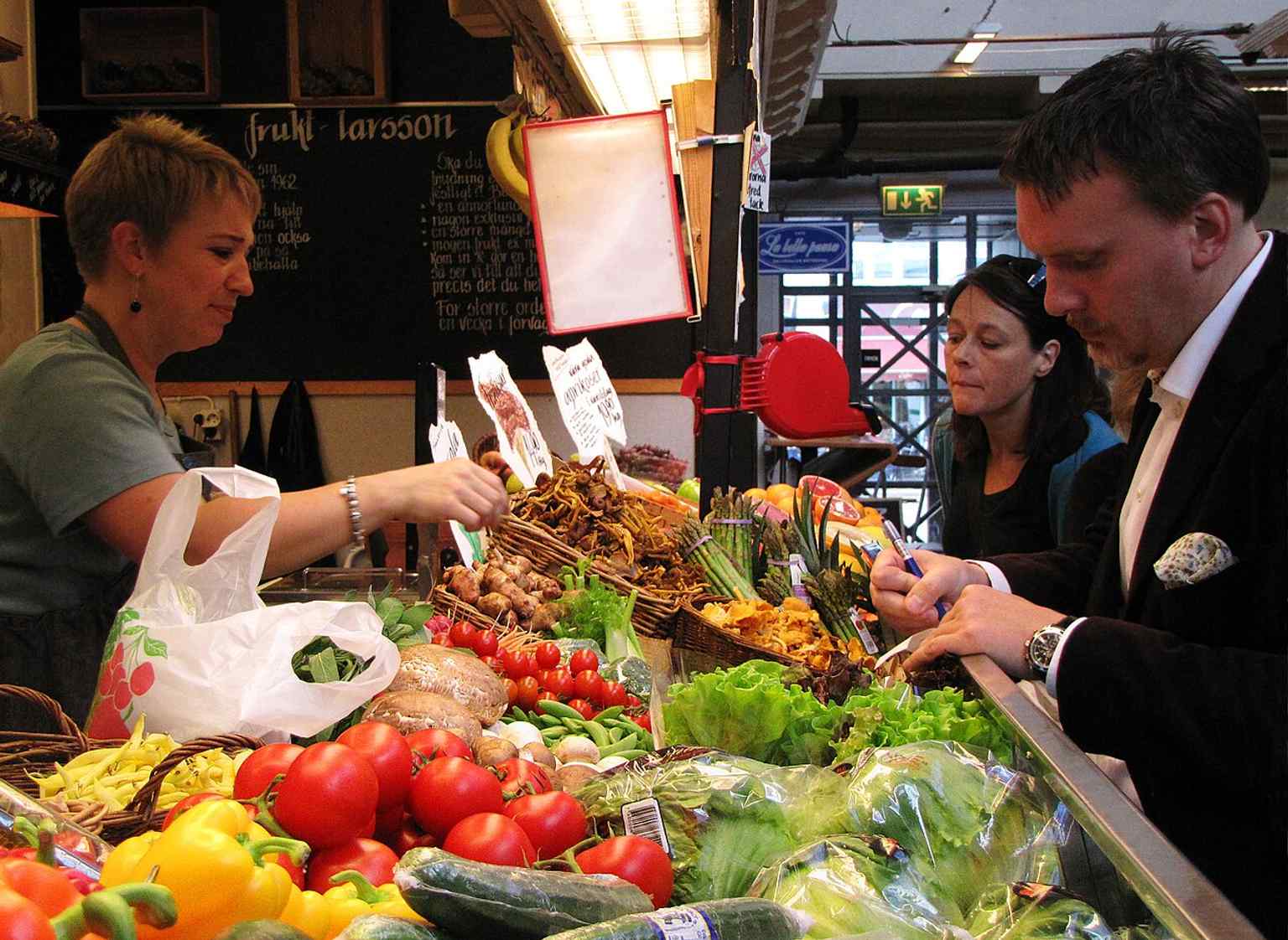 A vibrant greengrocer's stand inside Saluhallen, reflecting the market's long tradition of fresh produce, with Frukt Larsson being a notable merchant today.