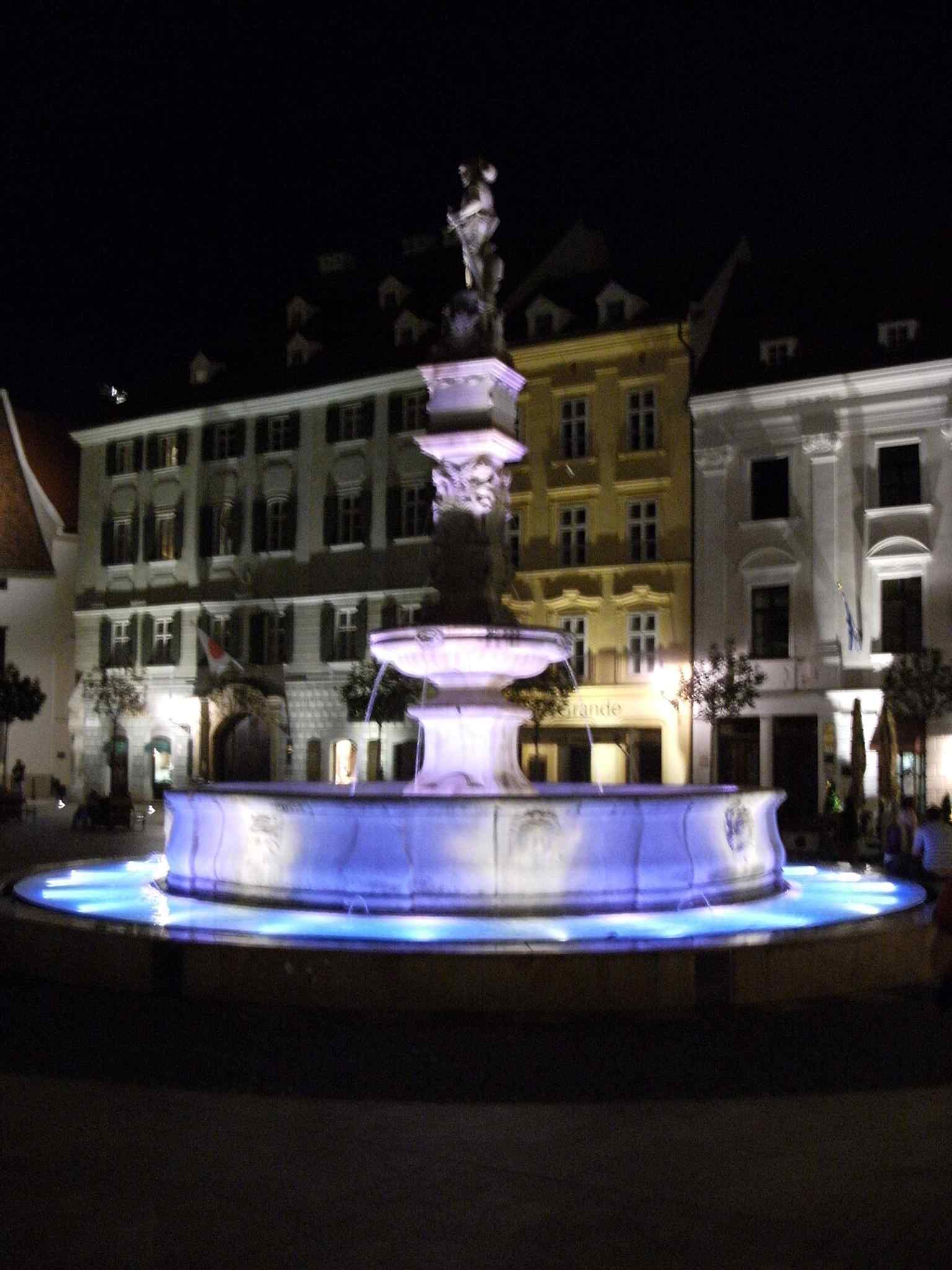 A strong full view of the Renaissance fountain, useful for showing its round basin and central knight figure in one frame.