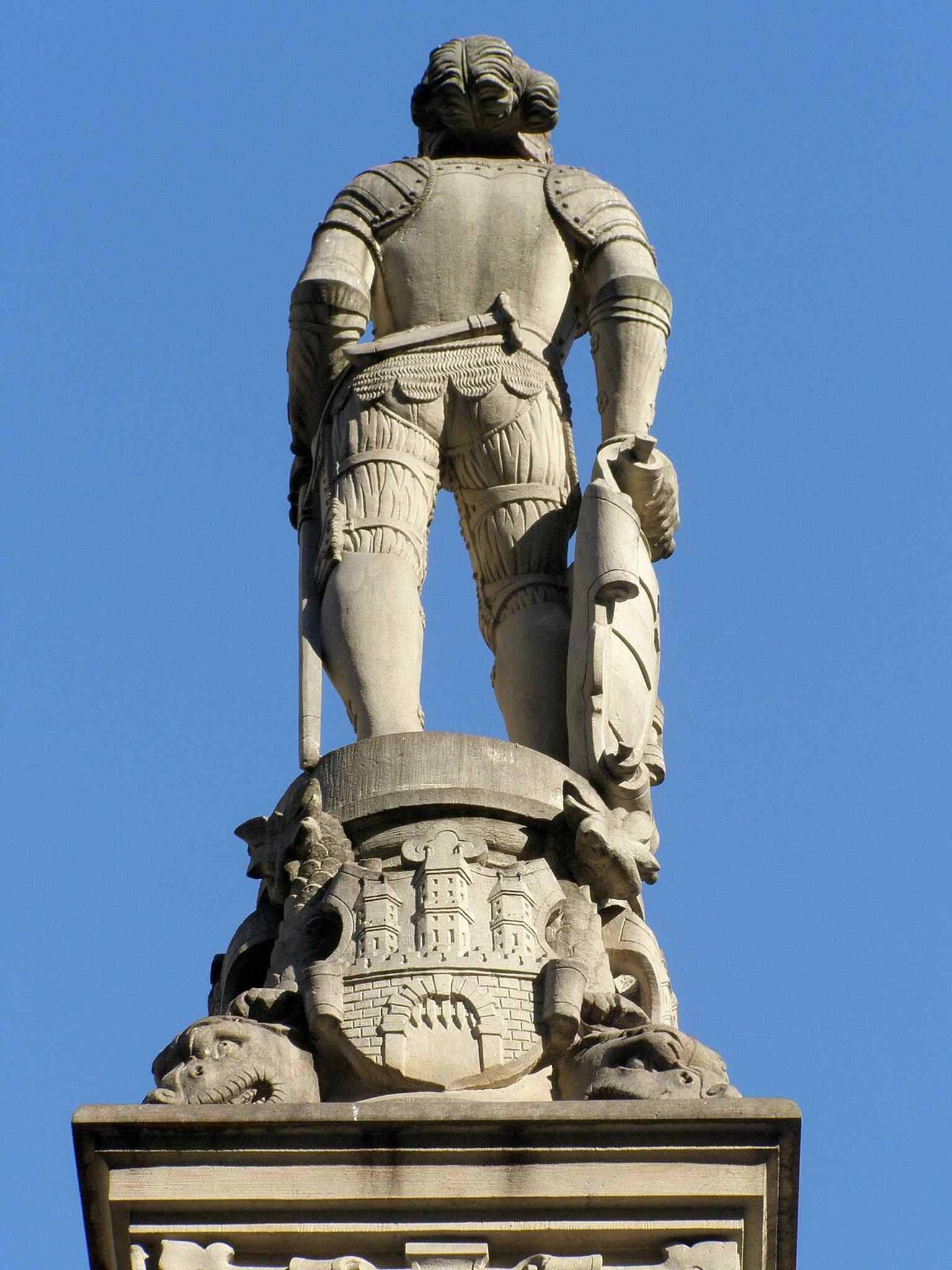 A close image of the fountain’s decorative stonework, where the carved coat of arms reinforces the monument’s royal dedication.