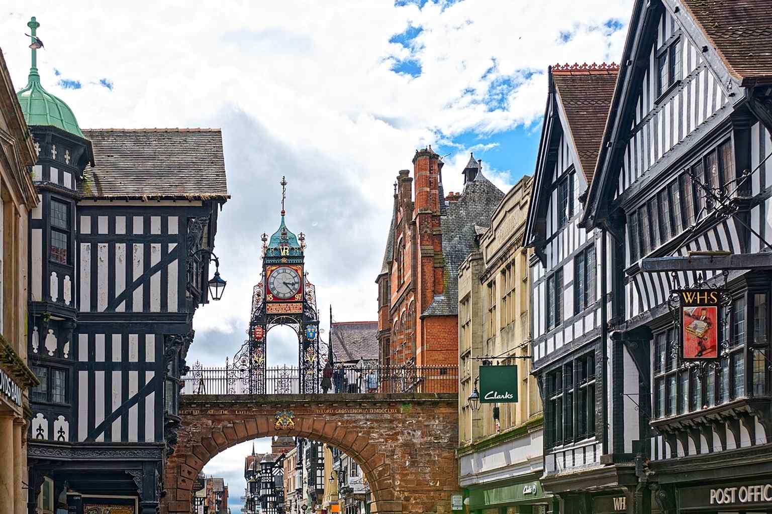 A crisp modern view of Eastgate and the clock, showing the three-arched gateway carrying the city walls walkway above Chester’s busiest historic entrance.